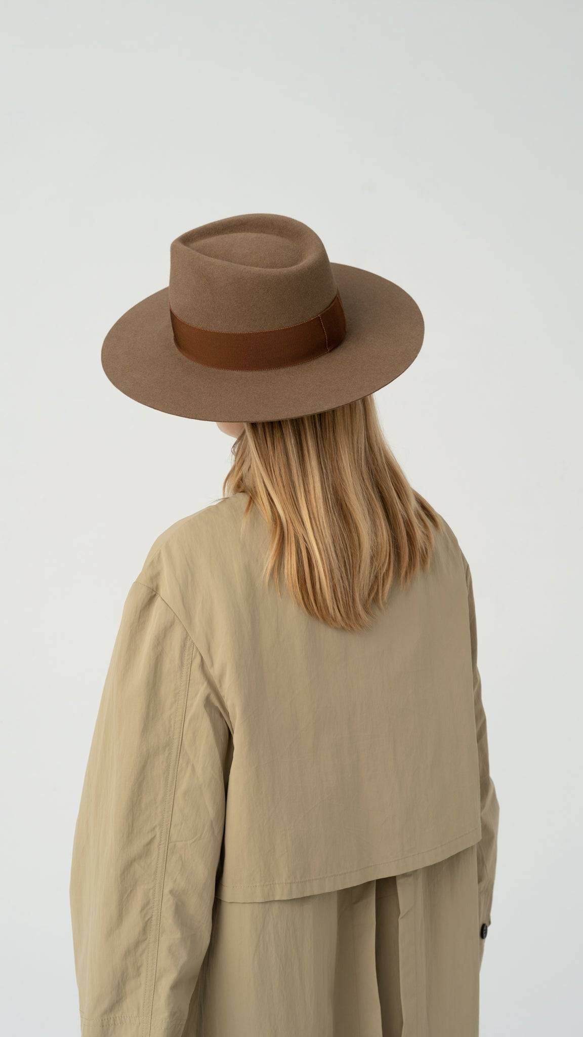 Back view of a walnut fedora hat with a brown band, elegantly paired with a beige trench coat. Made from premium rabbit fur felt for a classic look.