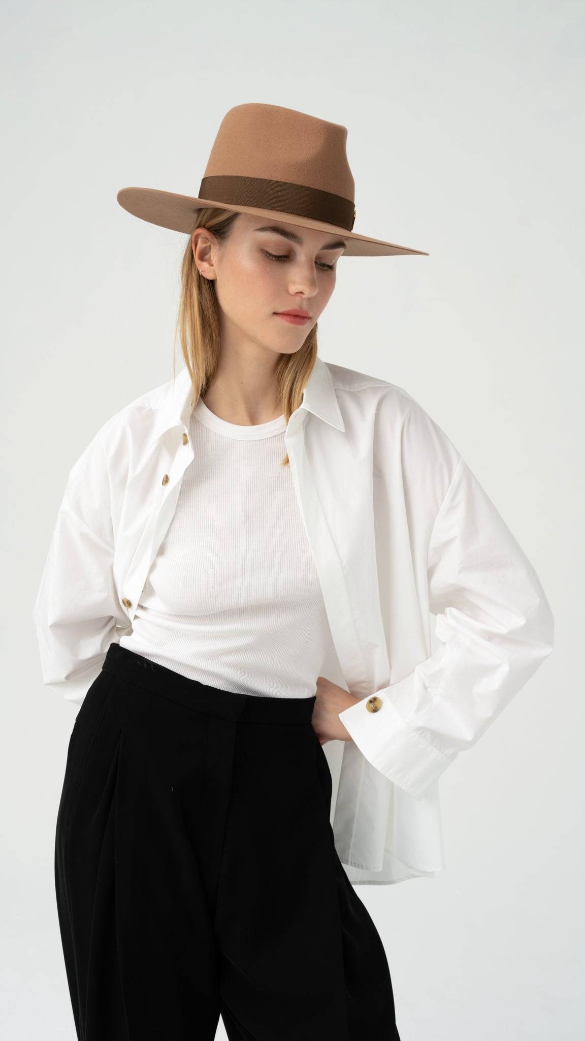 Model wearing the Monogram embellished brown fedora hat with a wide-brim design. A stylish accessory paired with a white shirt and black trousers.