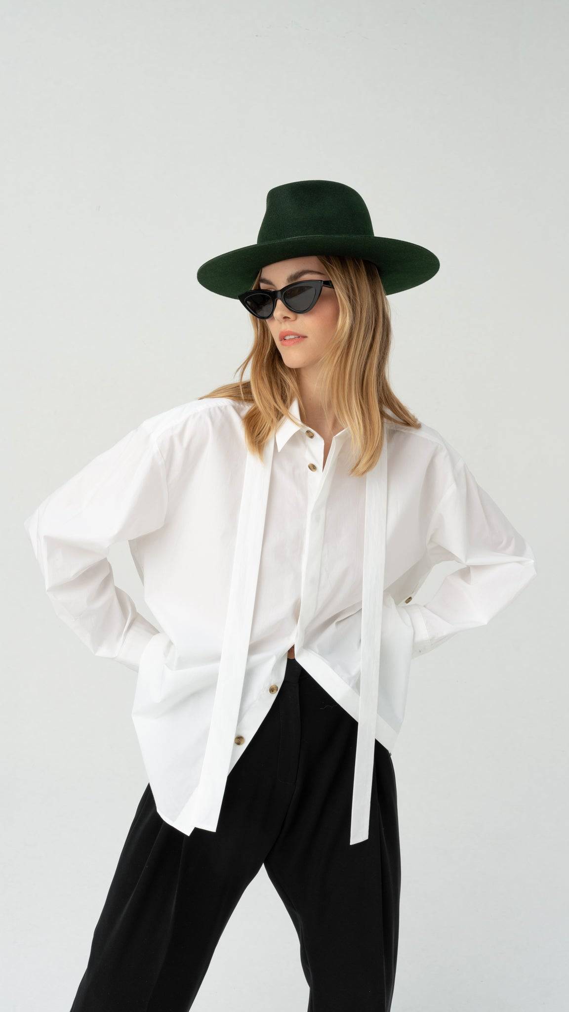 Dark green fedora hat styled with a white oversized shirt and black trousers. A chic and versatile accessory for any season.