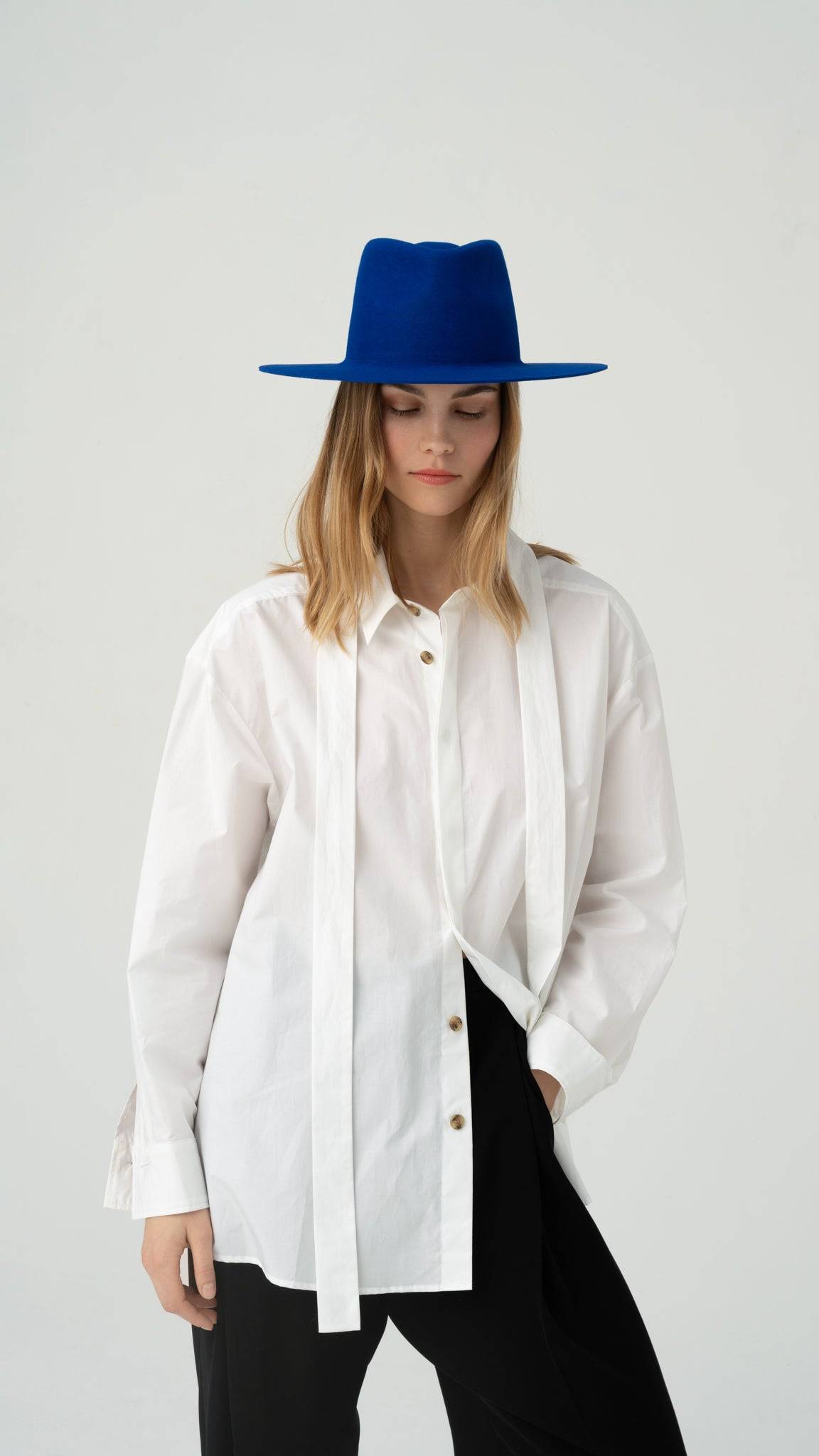 Elegant royal blue fedora hat paired with a white button-up shirt. A statement accessory crafted from premium rabbit fur felt.