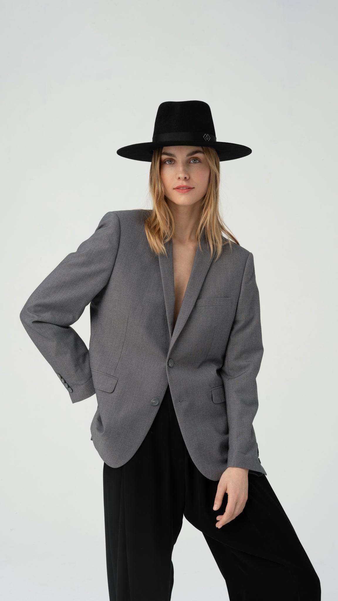 Monogram black fedora hat styled with a gray blazer and black trousers. Handcrafted rabbit fur felt with heart monogram detail. Shop now for 10% off.