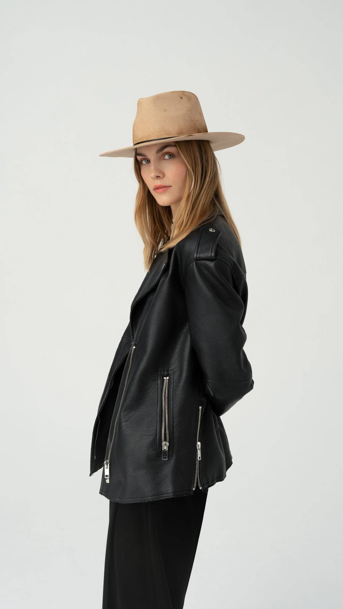 Distressed nude fedora hat styled with a black leather jacket. Handcrafted from rabbit fur felt, featuring leather strings and a peacock feather.