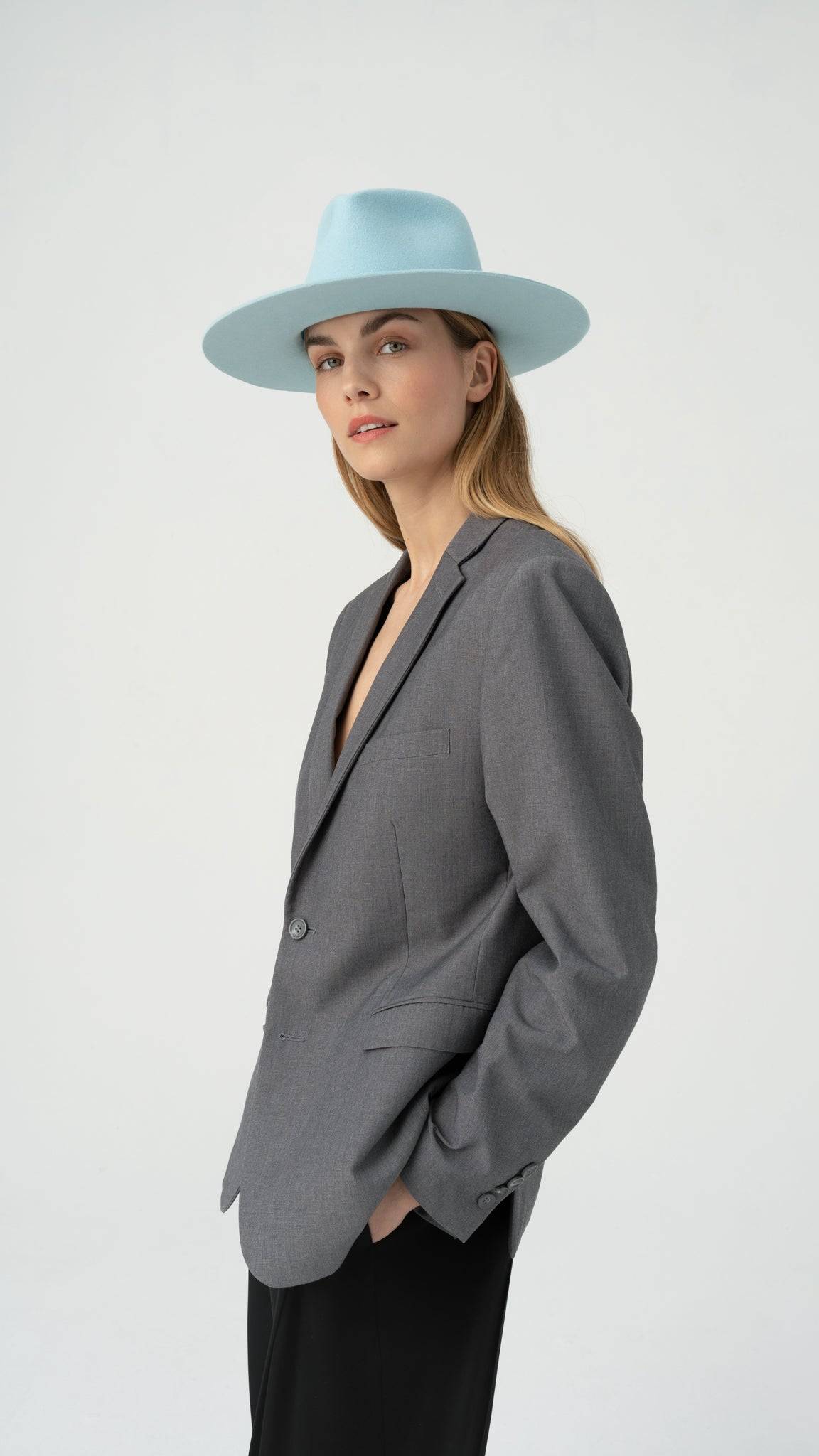 Side view of Sky Blue Borisetti Fedora Hat paired with a gray blazer. A luxury handcrafted hat designed for timeless elegance and style.