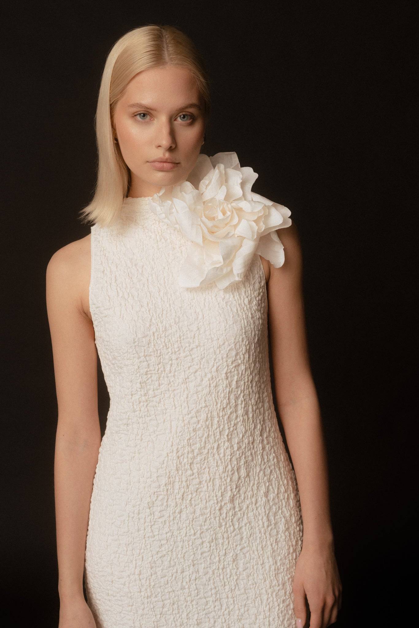 Ivory Silk Rose flower brooch elegantly adorns a textured white dress, adding a sophisticated touch. A perfect handcrafted bridal accessory.