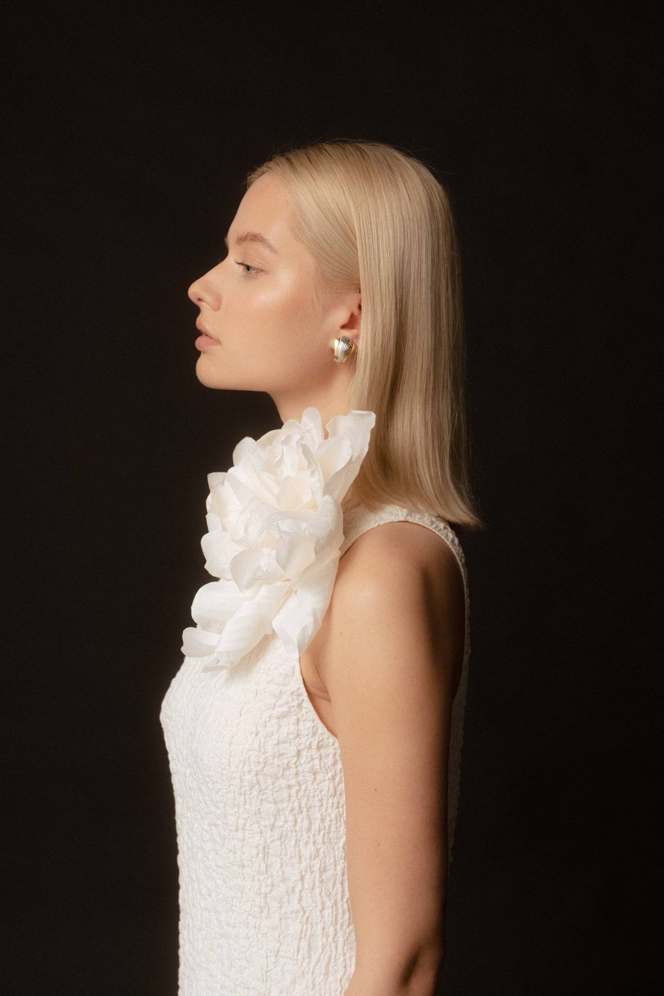 Side profile showcasing the Ivory Silk Rose flower brooch on a white dress. A stylish and elegant handcrafted bridal accessory.