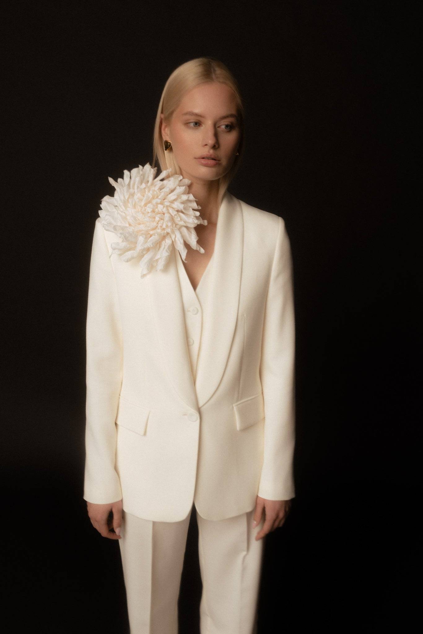 White Silk Flower Brooch elegantly adorns a tailored ivory blazer. Handcrafted bridal accessory adds sophistication to formal attire.