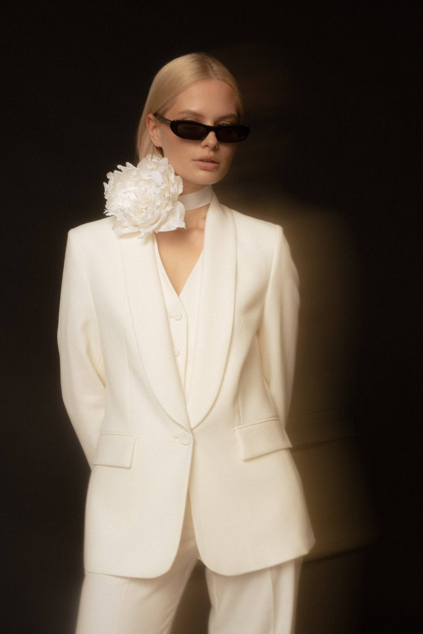 Elegant Borisetti Silk Peony Brooch & Choker, a white silk flower accessory styled with a chic suit and sunglasses. Order now online.