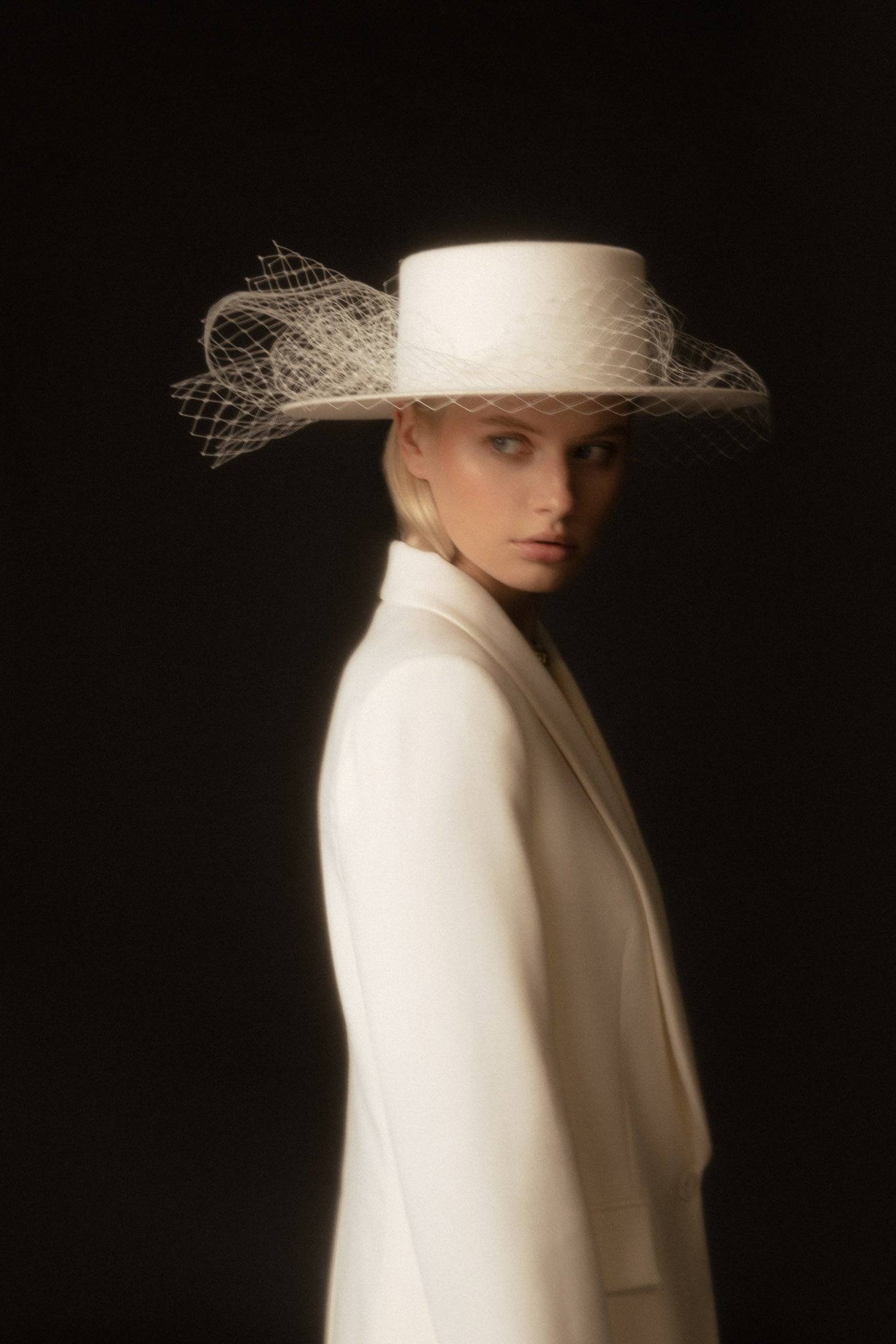 Ivory boater hat with a removable veil, designed for brides seeking a timeless and sophisticated wedding accessory.