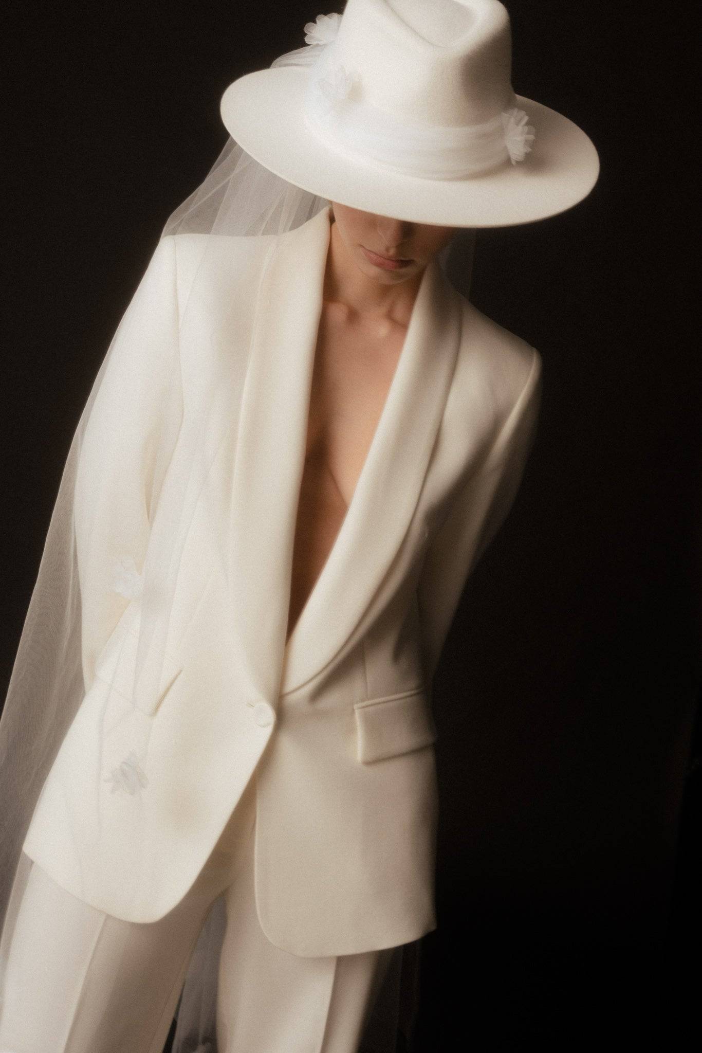 Ivory bridal fedora hat with a delicate removable veil, featuring handcrafted floral details. A luxury wedding accessory for the modern bride.