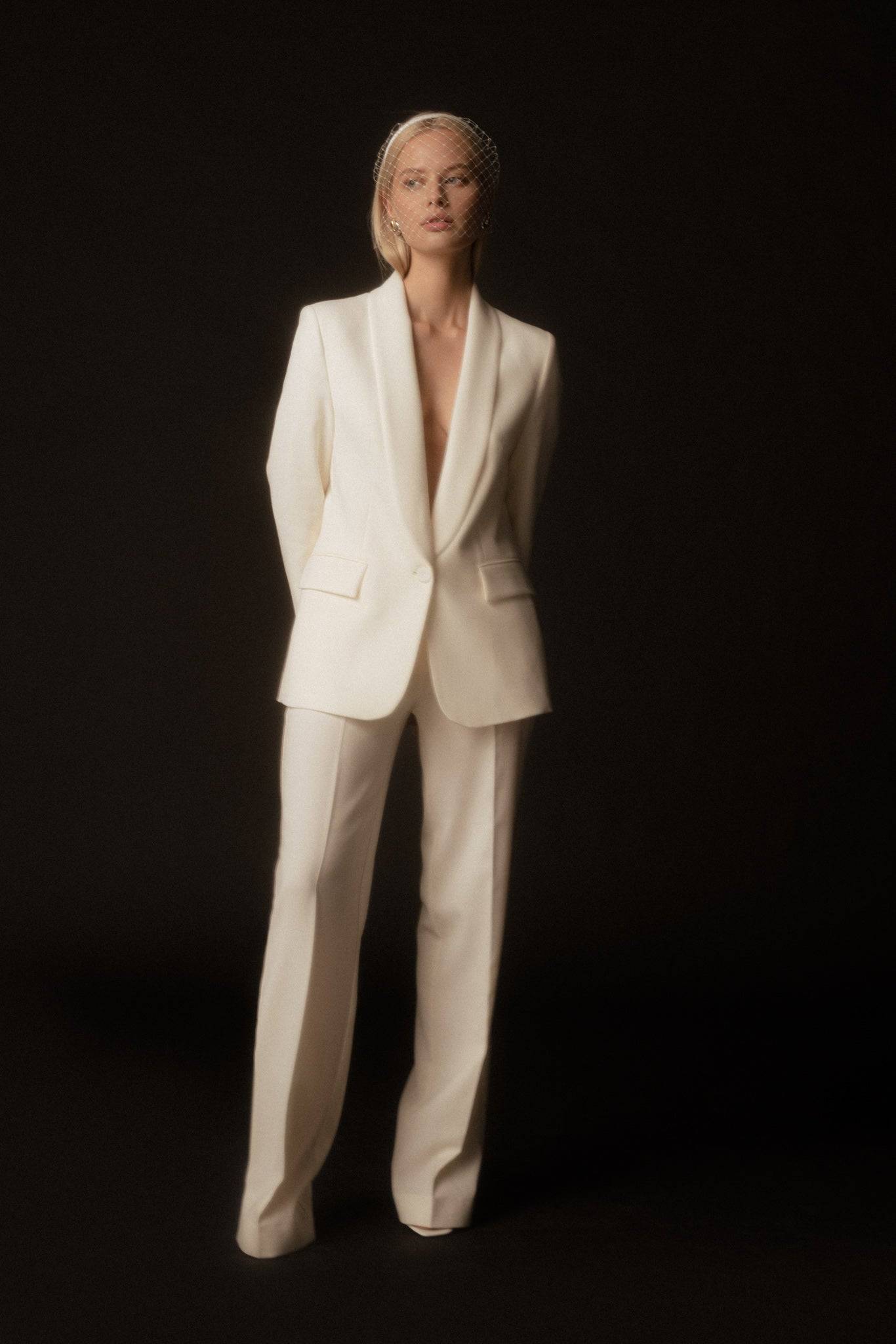 Ivory veil-detail satin silk headband styled with a white tailored suit. A chic and modern bridal or event accessory for a refined look.
