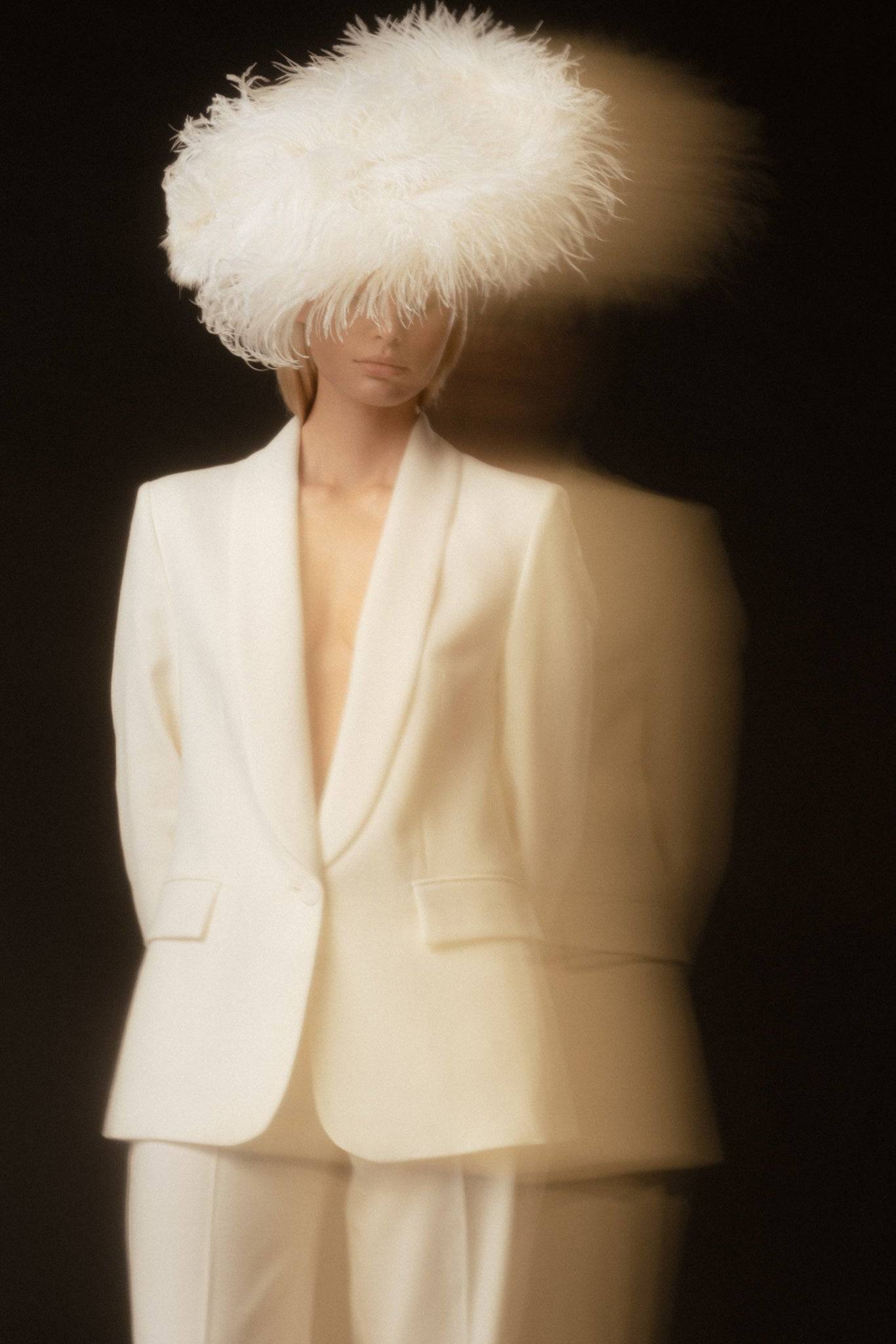 Ethereal bridal look with a handcrafted ostrich feather headpiece and cream suit. A couture wedding accessory for a bold and elegant statement.