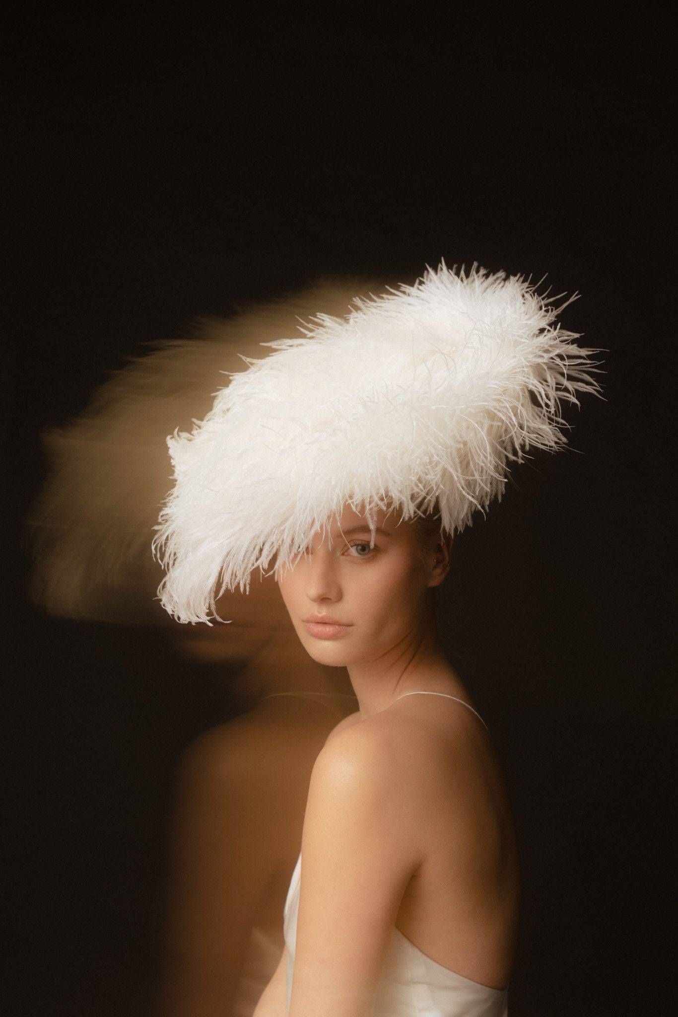 Close-up of a bride in a white ostrich feathered headpiece, exuding timeless elegance. A unique couture bridal hair accessory for modern weddings.