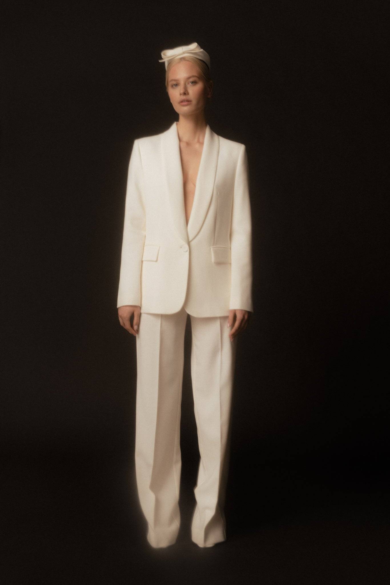 Full-length bridal look featuring an ivory pillbox hat with bow. A vintage-inspired wedding accessory for timeless elegance.