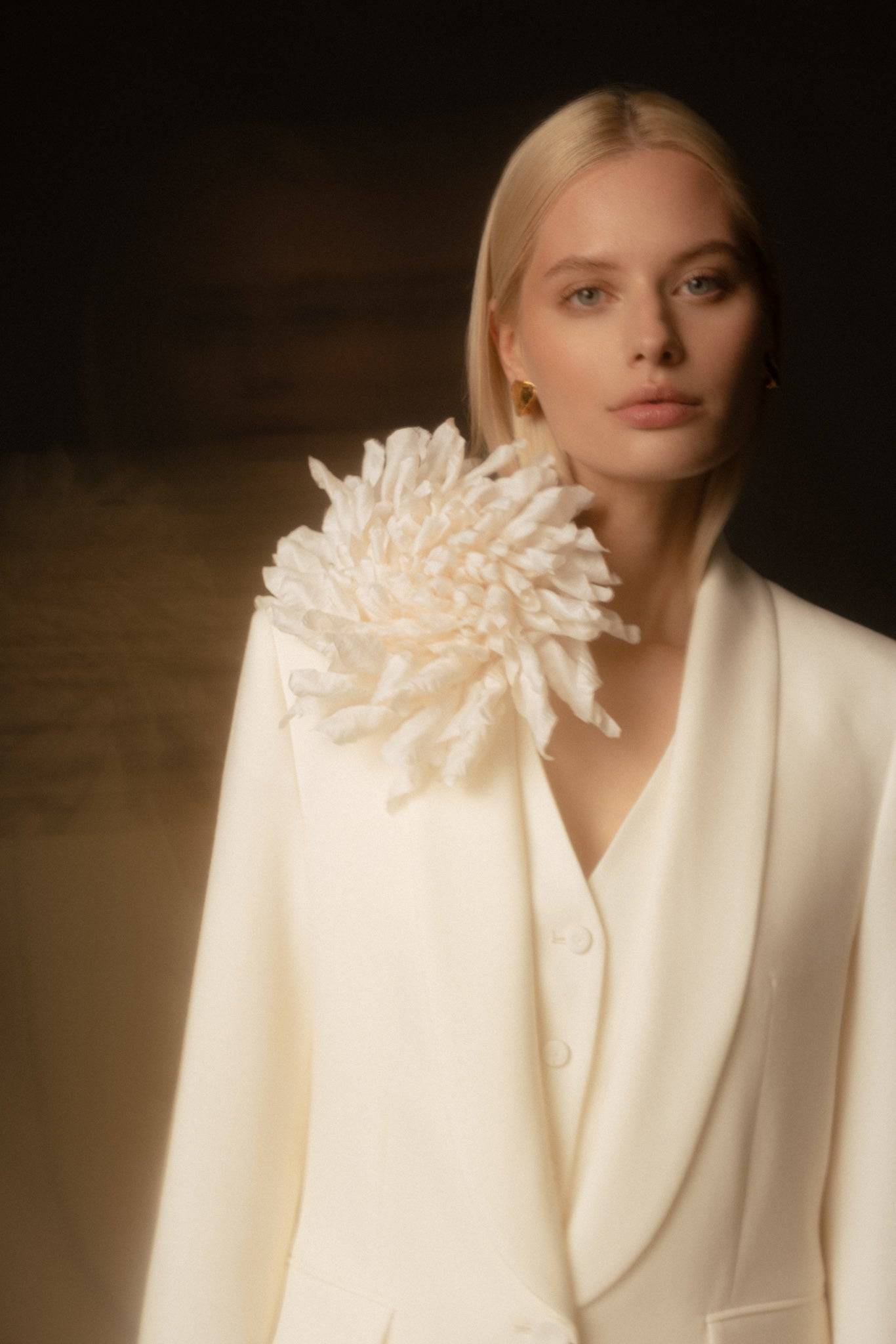 Close-up of White Silk Flower Brooch on an ivory blazer. Handcrafted elegance perfect for bridal or evening wear.