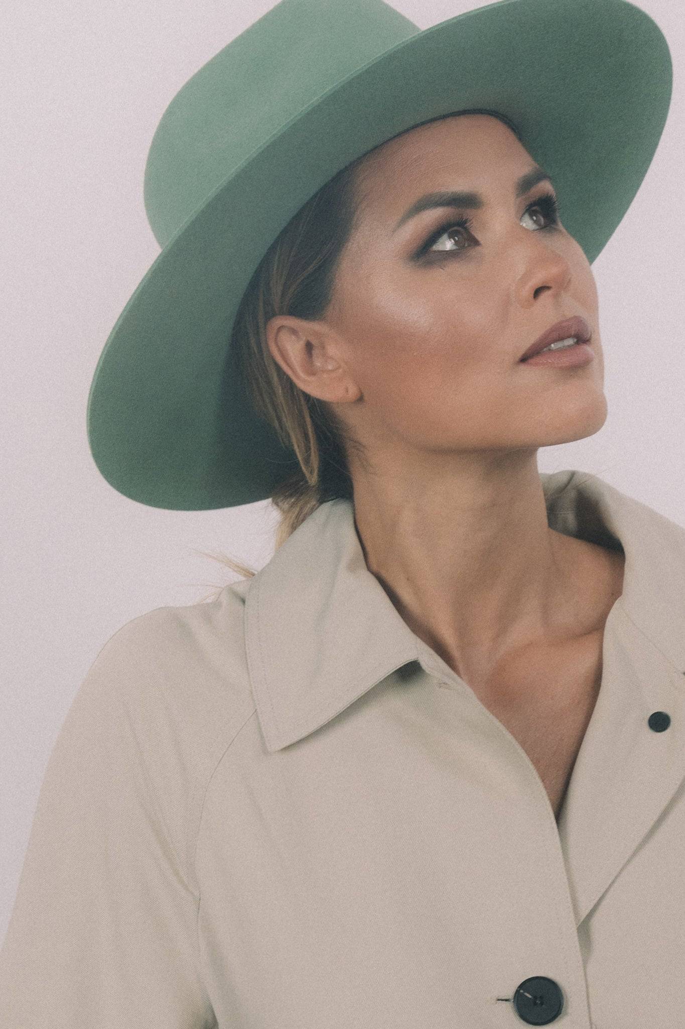 Close-up of Borisetti green fedora hat on a woman. A handcrafted rabbit fur felt fedora with a structured brim and elegant ribbon.