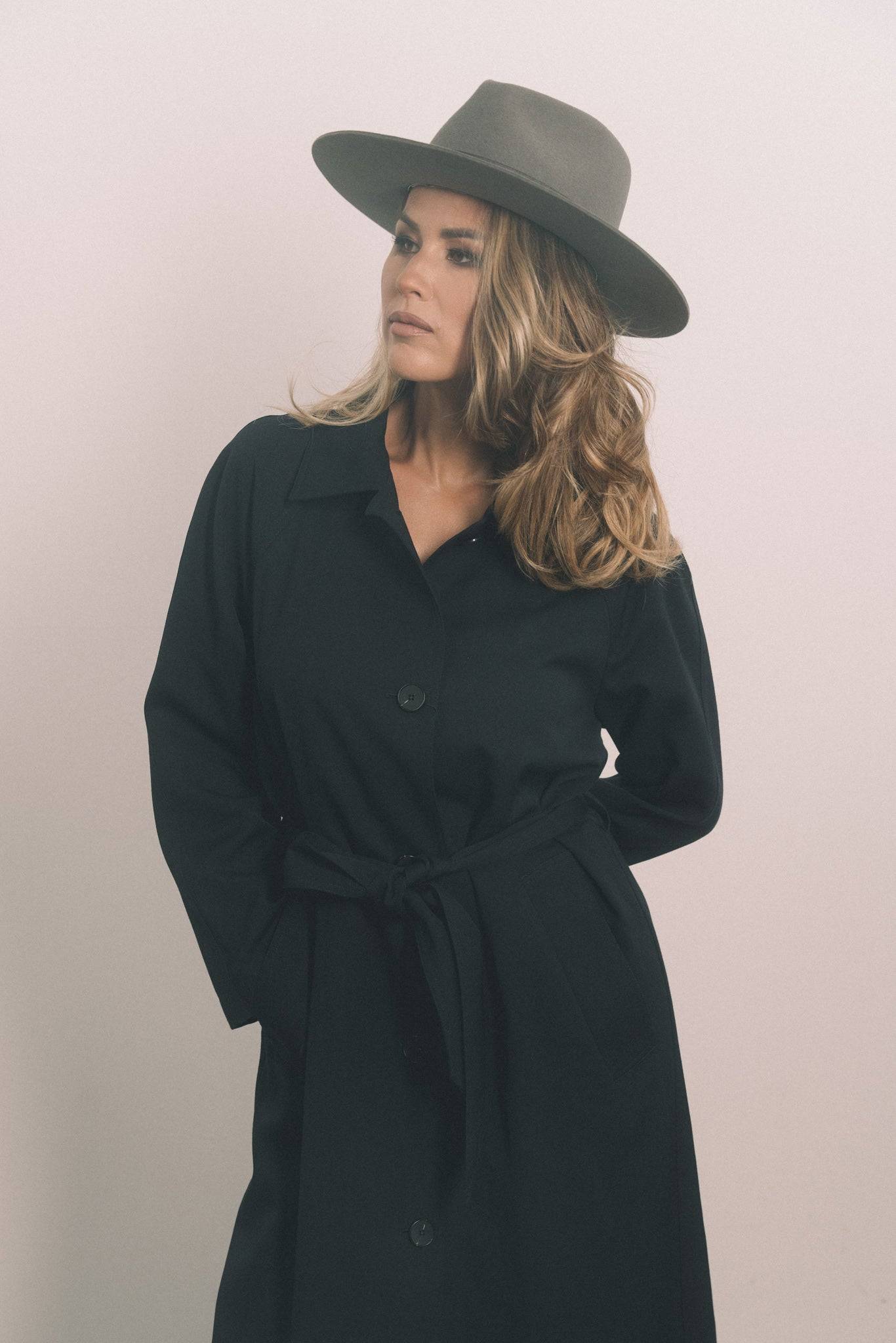 Classic grey fedora hat with ribbon embellishment, worn with a black coat. A sophisticated, custom-made piece for formal and casual wear. Buy now.