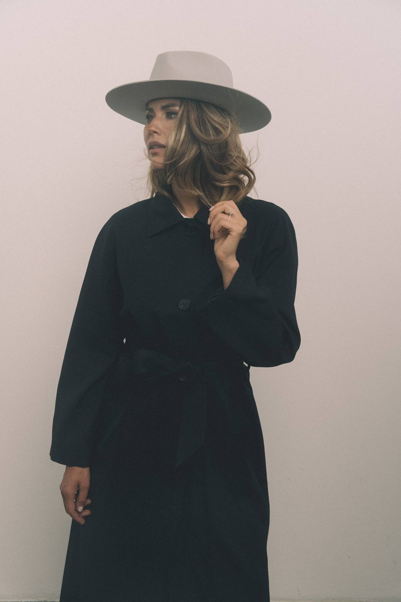Custom-made light grey fedora hat with a structured brim, styled with a black coat. A sophisticated and timeless fashion accessory.