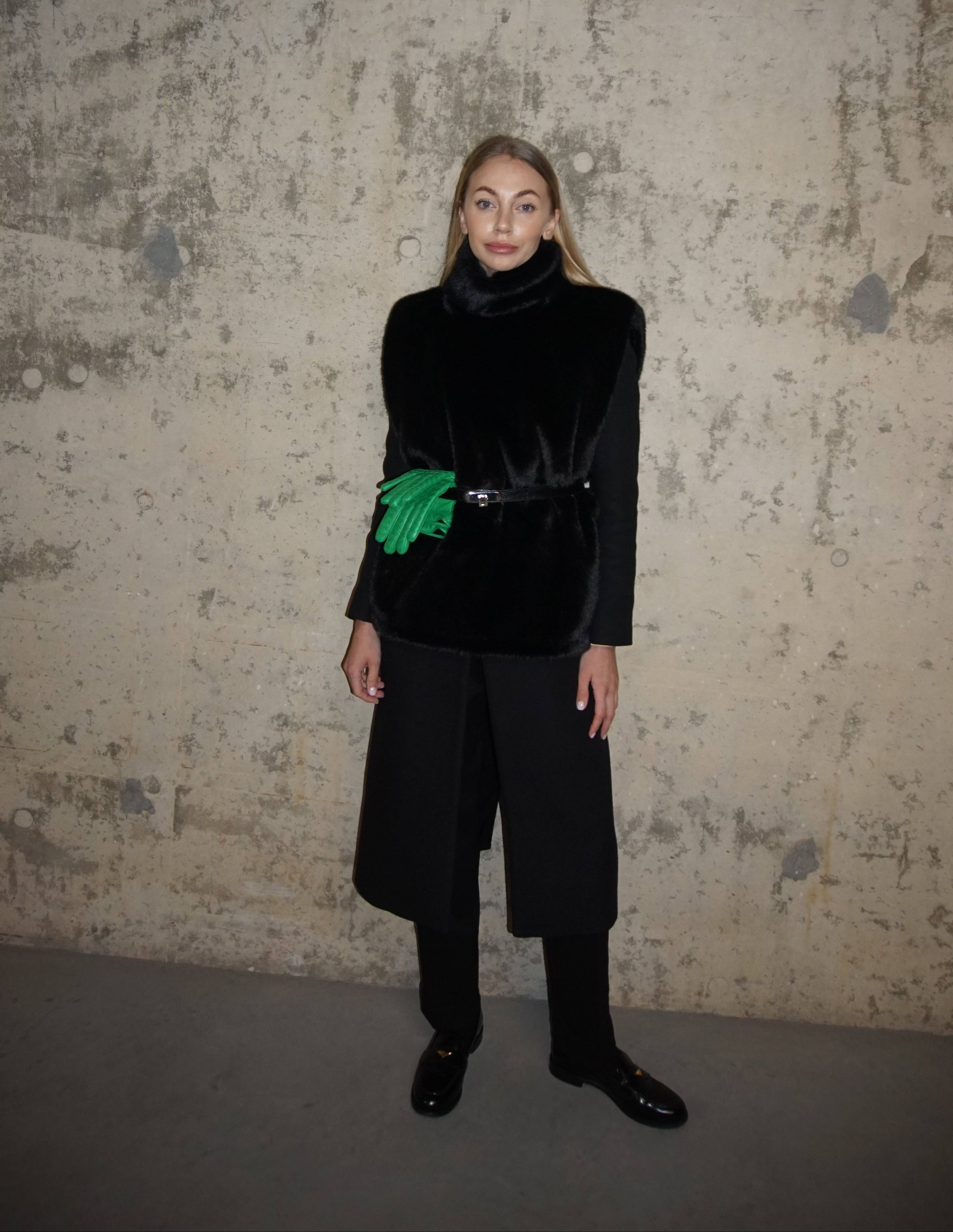 Black faux fur turtleneck styled with a structured coat and trousers, featuring a green clutch. A timeless winter accessory for warmth and elegance.