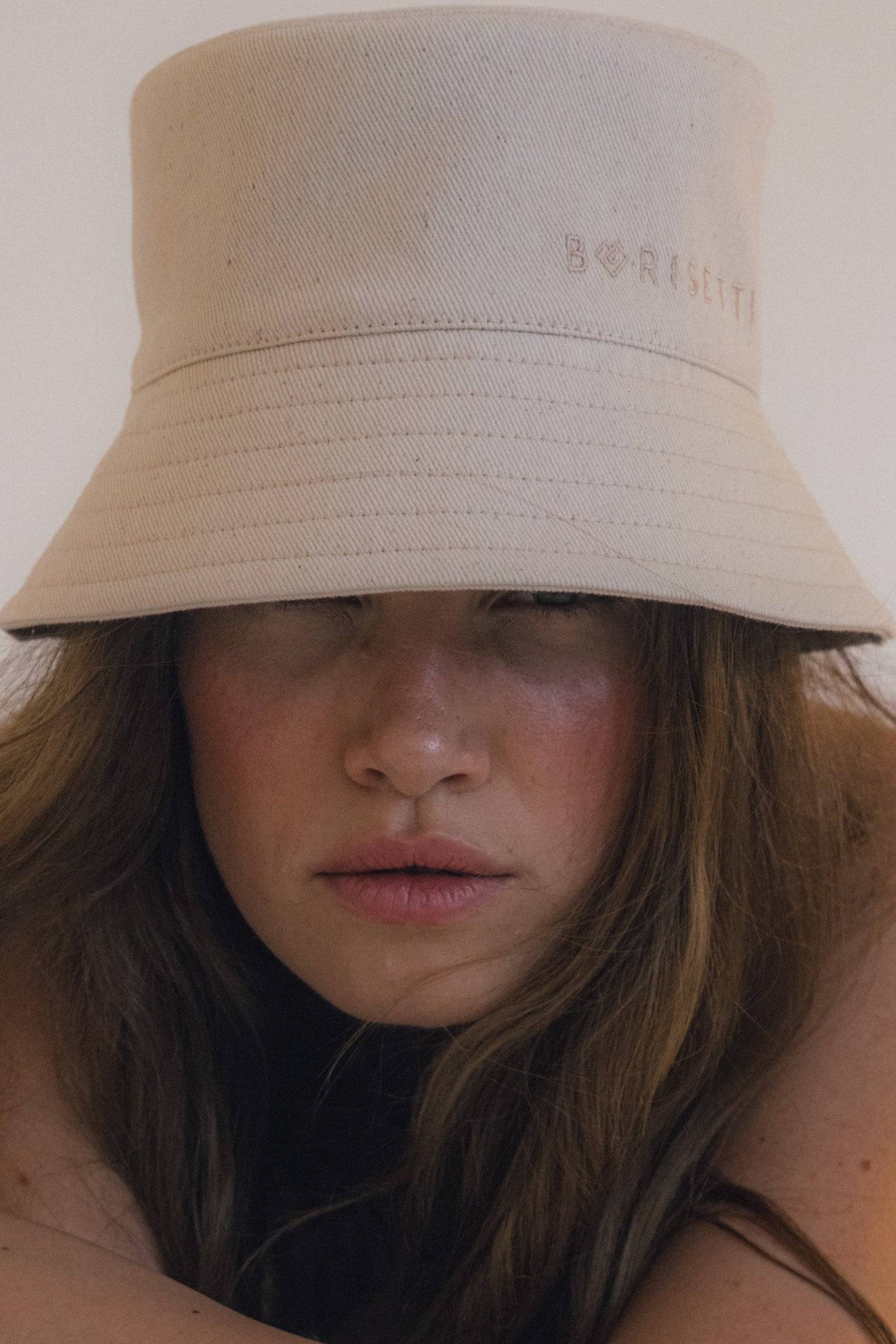 Beige denim bucket hat with embroidered Borisetti logo, styled with casual fashion. Handcrafted cotton design for everyday wear.
