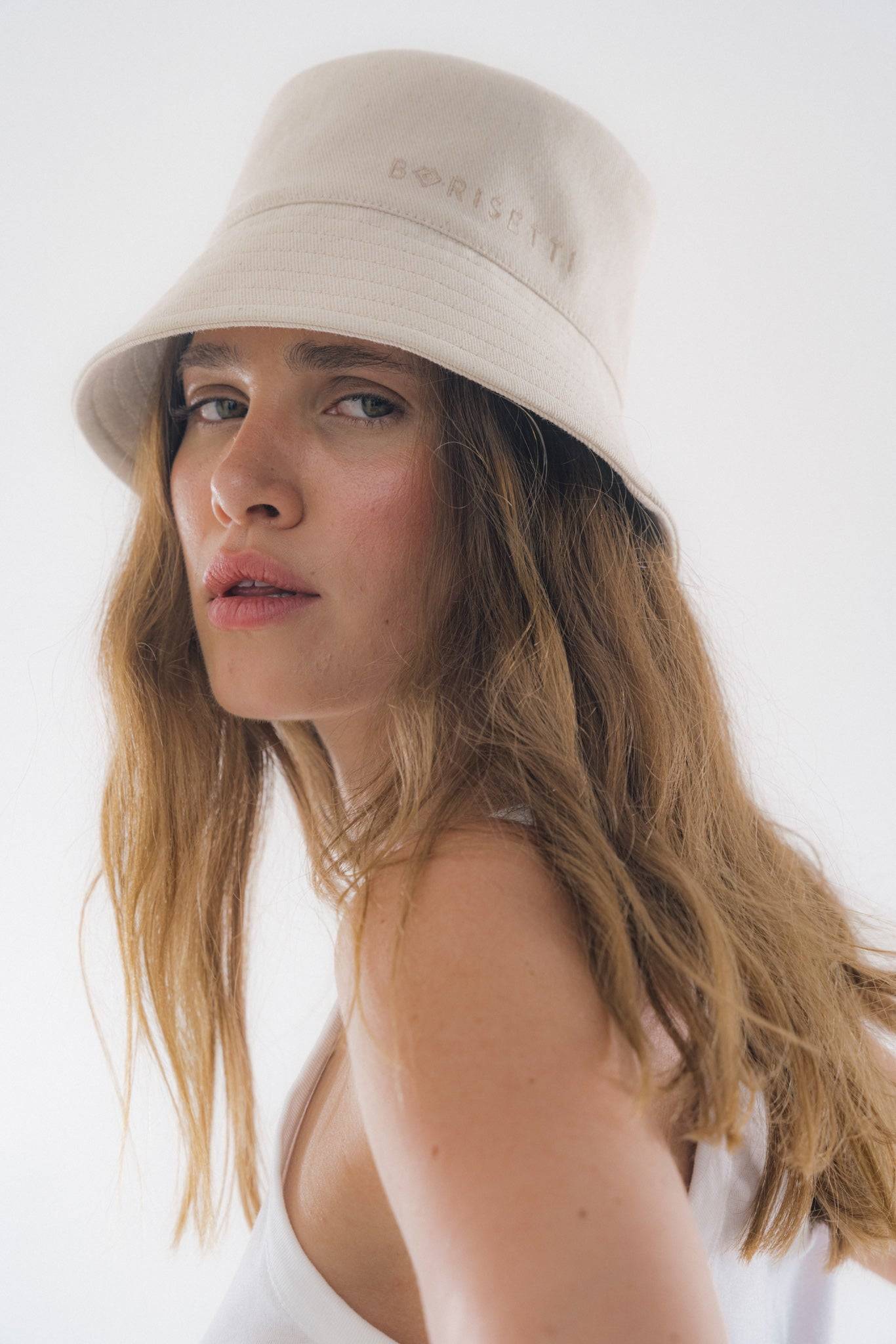 Light beige bucket hat with embroidered details, styled with casual wear. A perfect blend of comfort and high-fashion headwear.