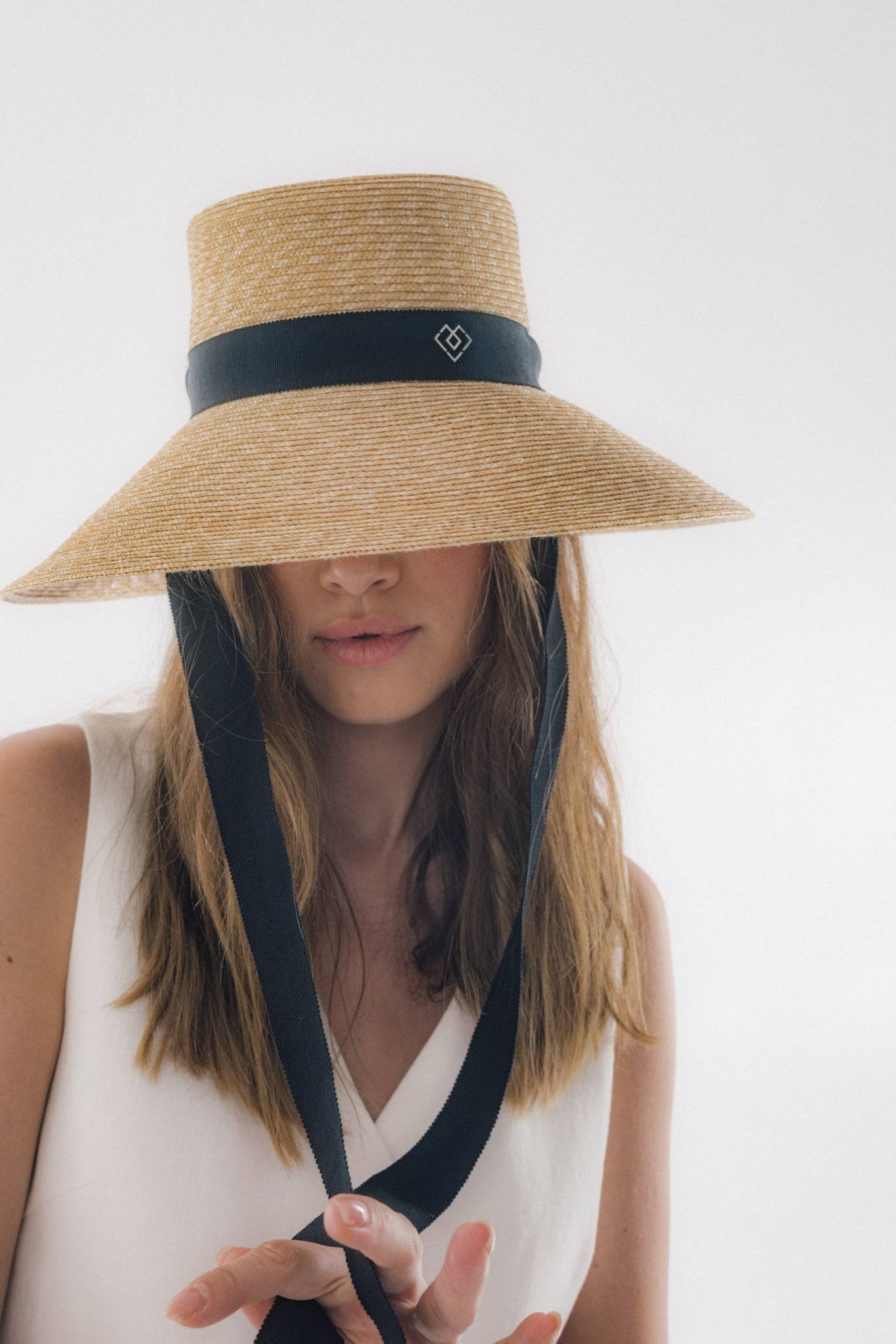 Chic neck tie wide brimmed straw hat with a black ribbon, offering timeless elegance and sun protection. Perfect for summer vacations and garden parties.