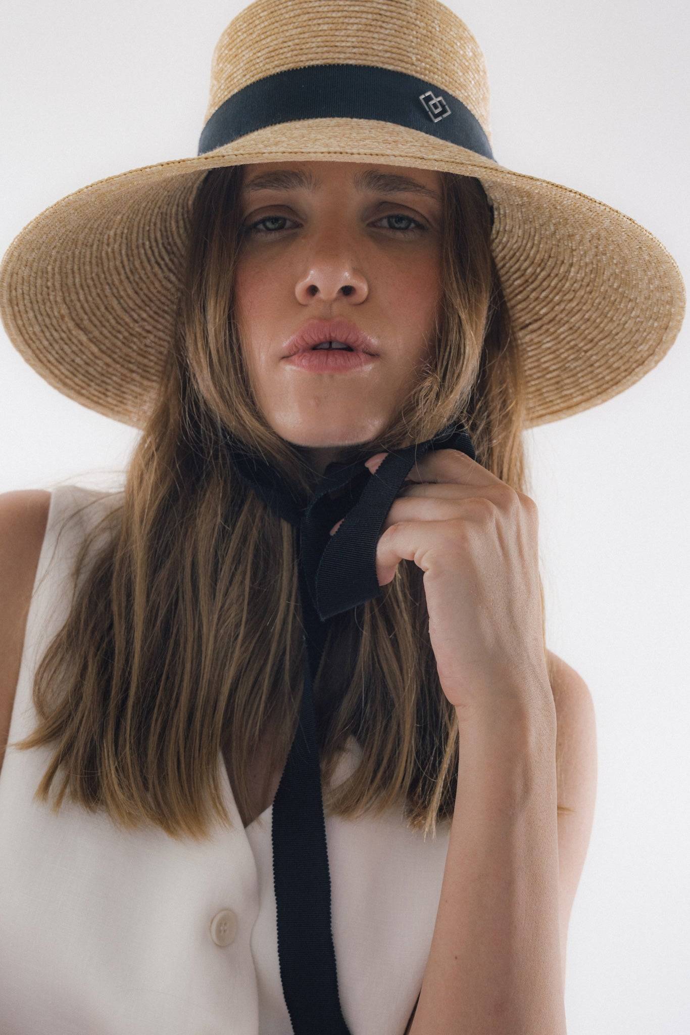 Chic neck tie wide brimmed straw hat with black ribbon, offering elegant sun protection. Perfect for summer, beach outings, and garden parties.