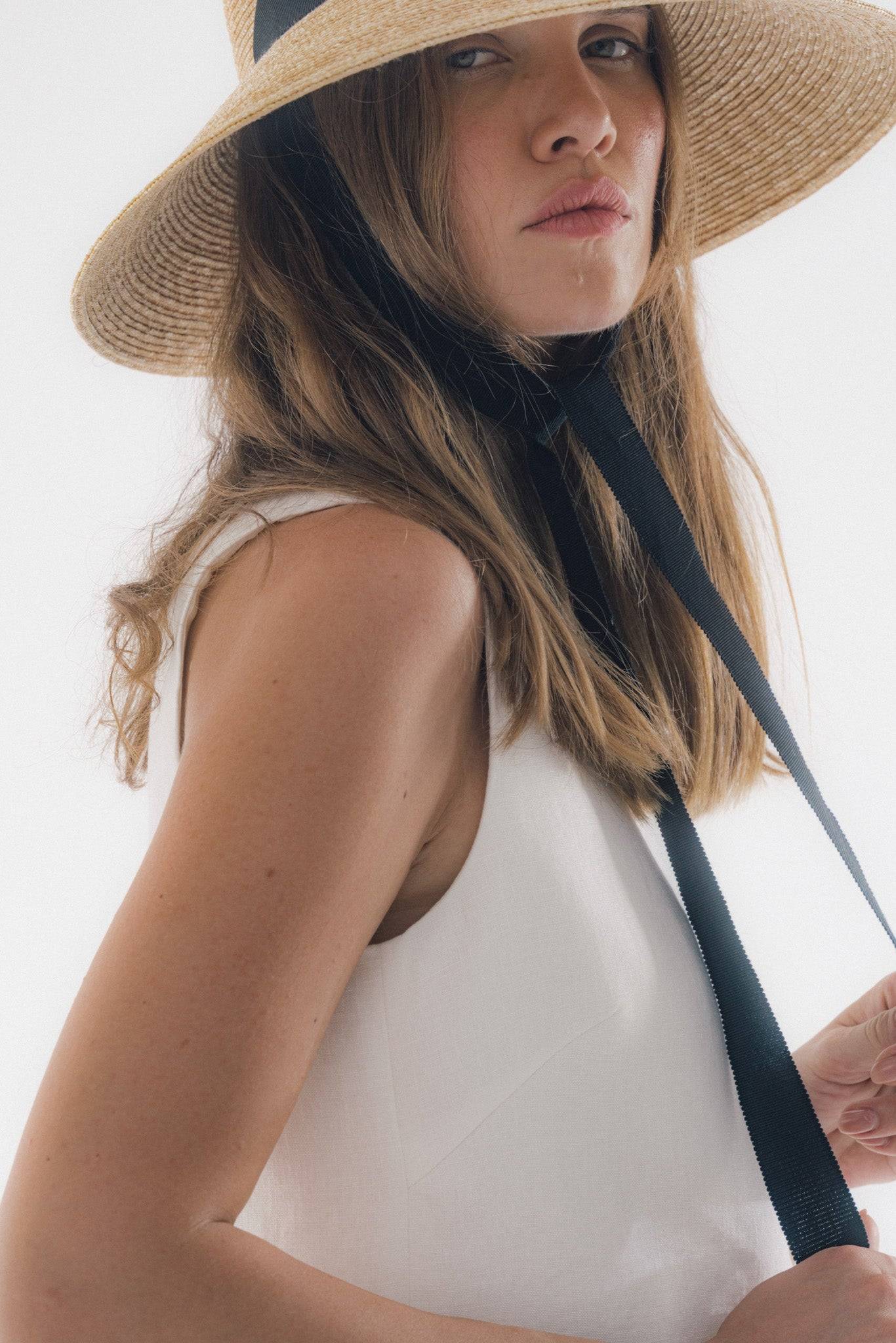 Chic neck tie wide brimmed straw hat with black ribbon, offering elegant sun protection. Perfect for summer vacations and garden parties.