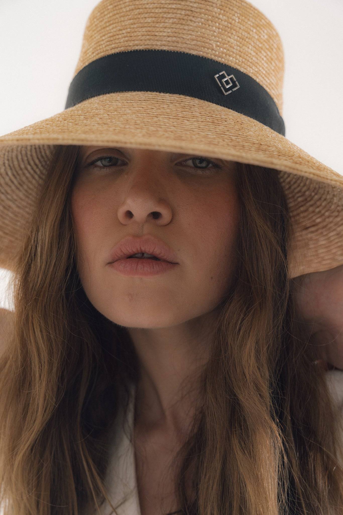 Chic neck tie wide brimmed straw hat with black ribbon and monogram detail, perfect for elegant summer style and sun protection.