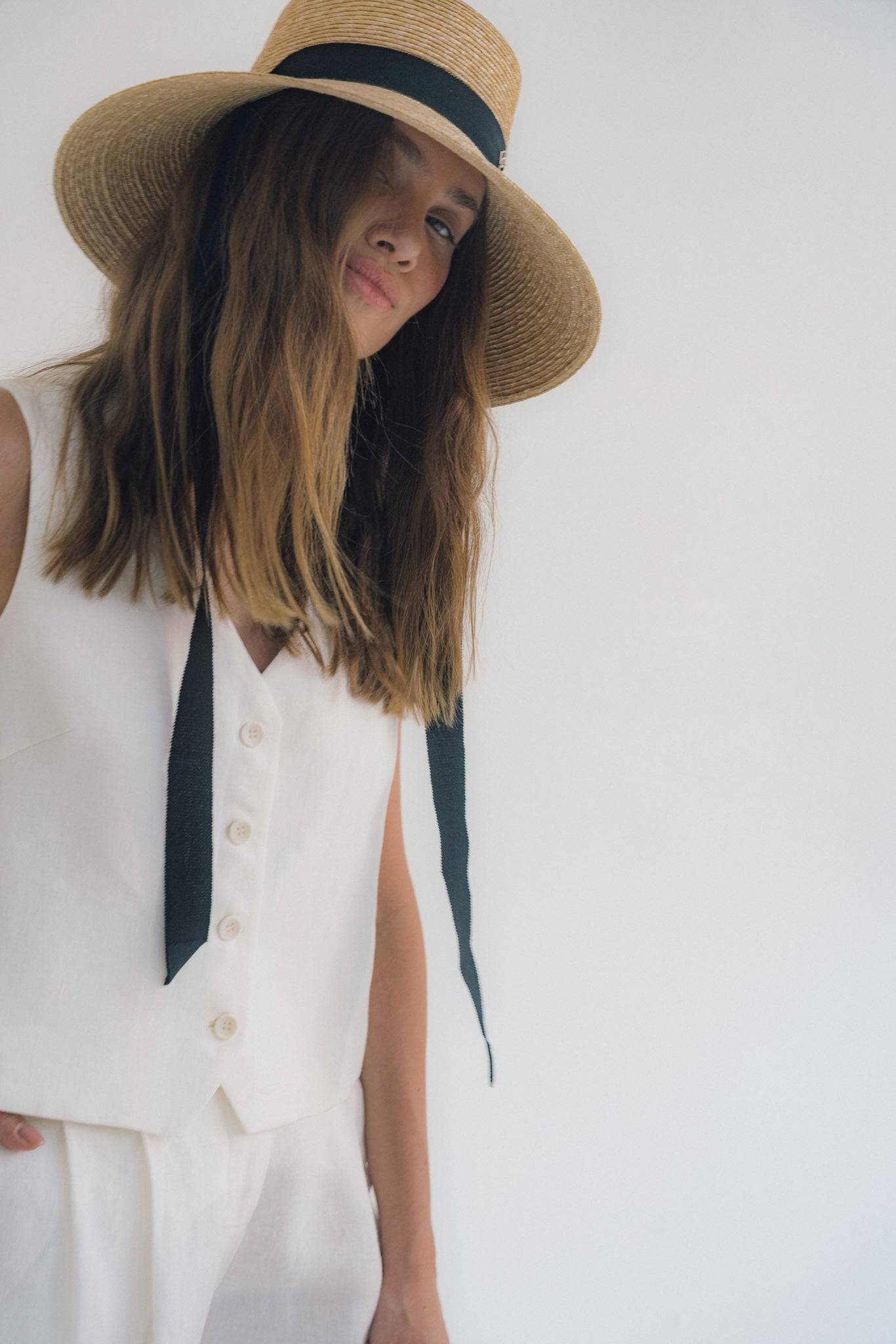 Chic neck tie wide brimmed straw hat with a black ribbon, perfect for summer elegance. Handcrafted natural straw sun hat for stylish sun protection.