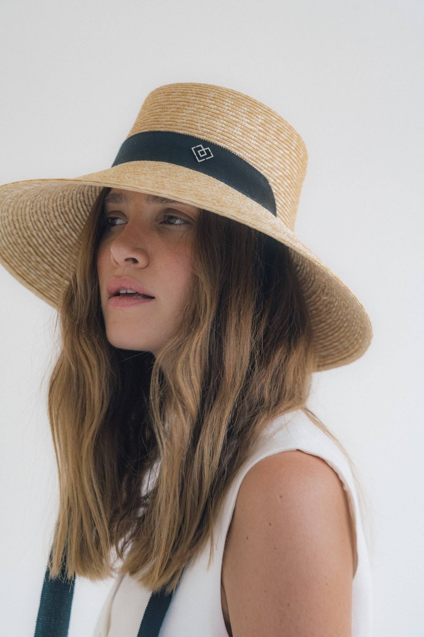 Chic neck tie wide brimmed straw hat with a black ribbon and monogram detail, perfect for sun protection and elegant summer styling.