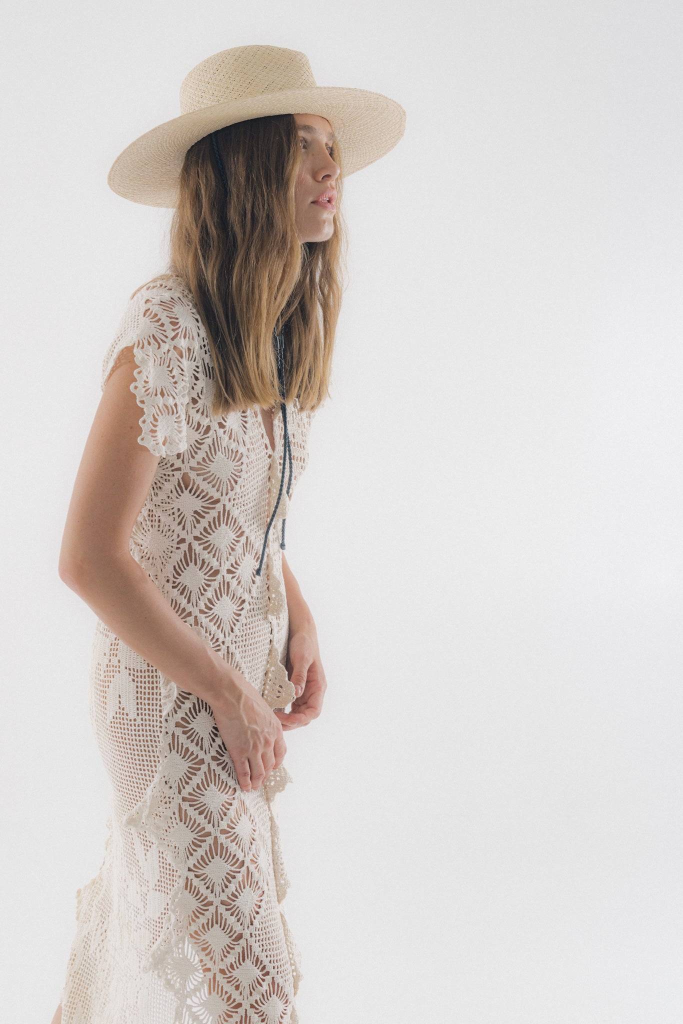 Wide-brimmed straw fedora hat with leather straps, styled with a crochet lace dress for a chic summer look. Handcrafted from Toquilla straw.
