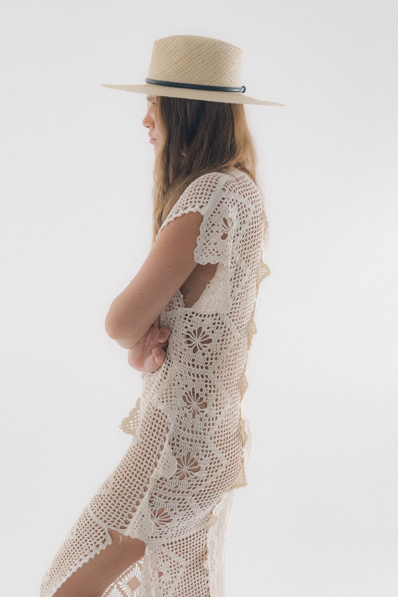 Side profile of a woman in a wide-brim straw fedora with a leather strap, styled with a crochet dress. A perfect blend of fashion and function.