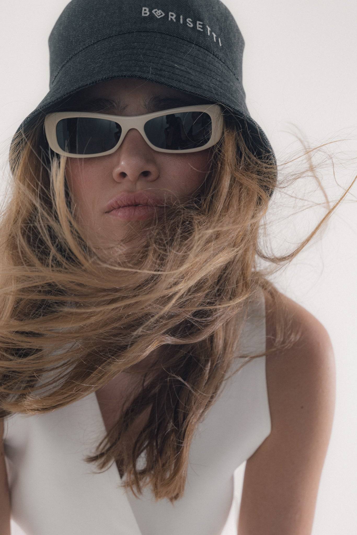 Close-up of a black denim bucket hat with Borisetti branding, styled with sunglasses. A fashionable and versatile accessory for any outfit.