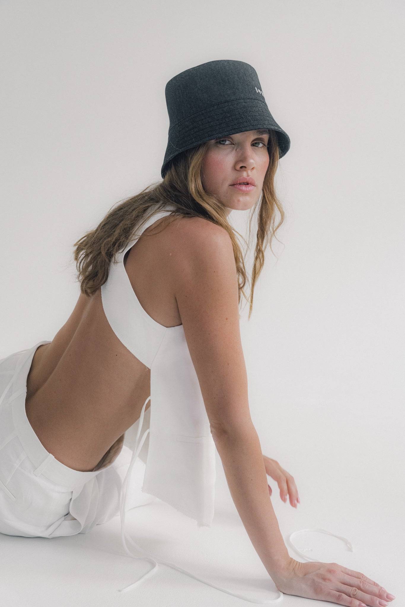 Black denim bucket hat with Borisetti embroidery, styled with a white outfit. Made from 100% cotton for a trendy and casual look.