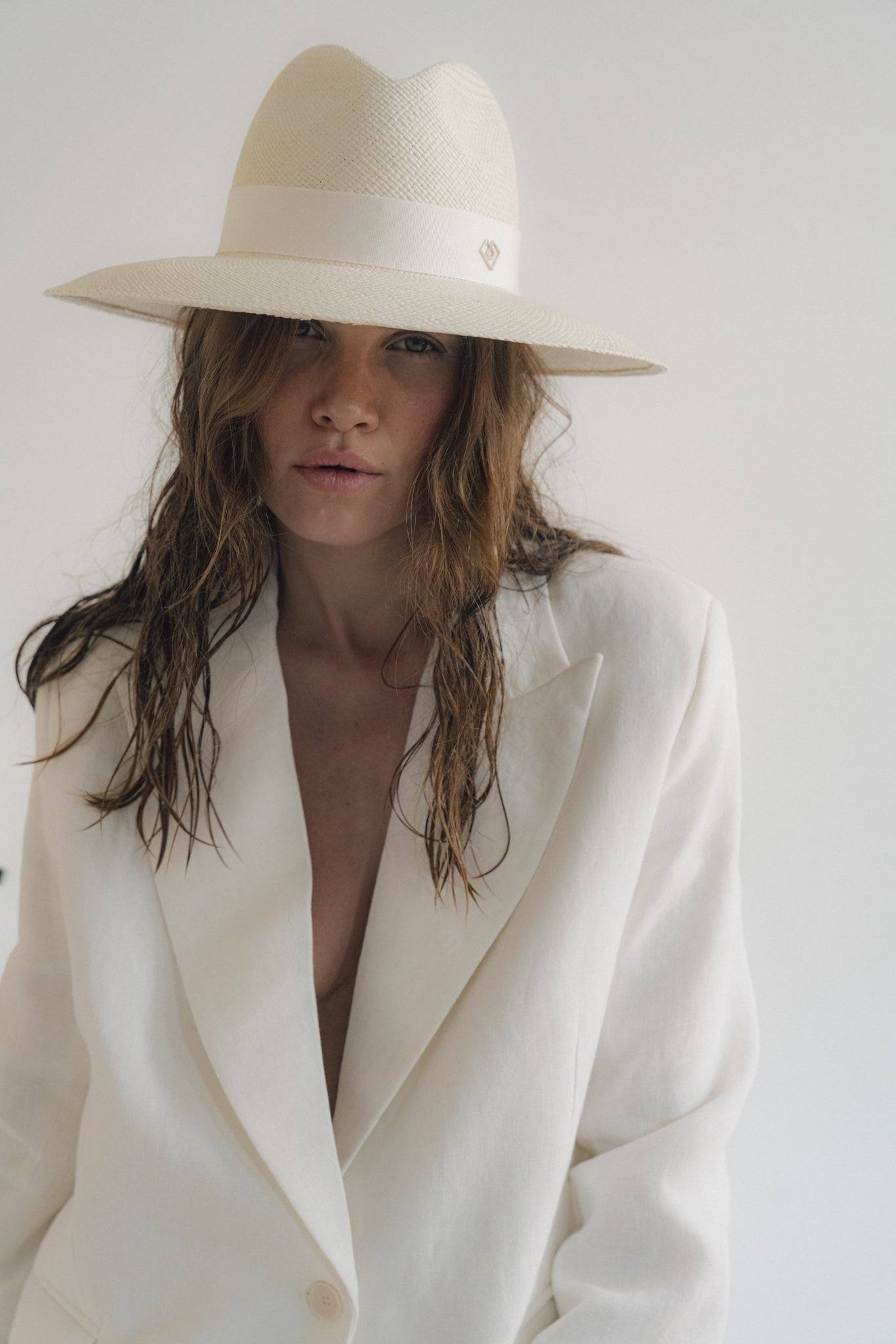 Elegant white wide-brimmed fedora hat paired with a chic white blazer. Handcrafted summer hat made from fine Toquilla straw for a timeless look.