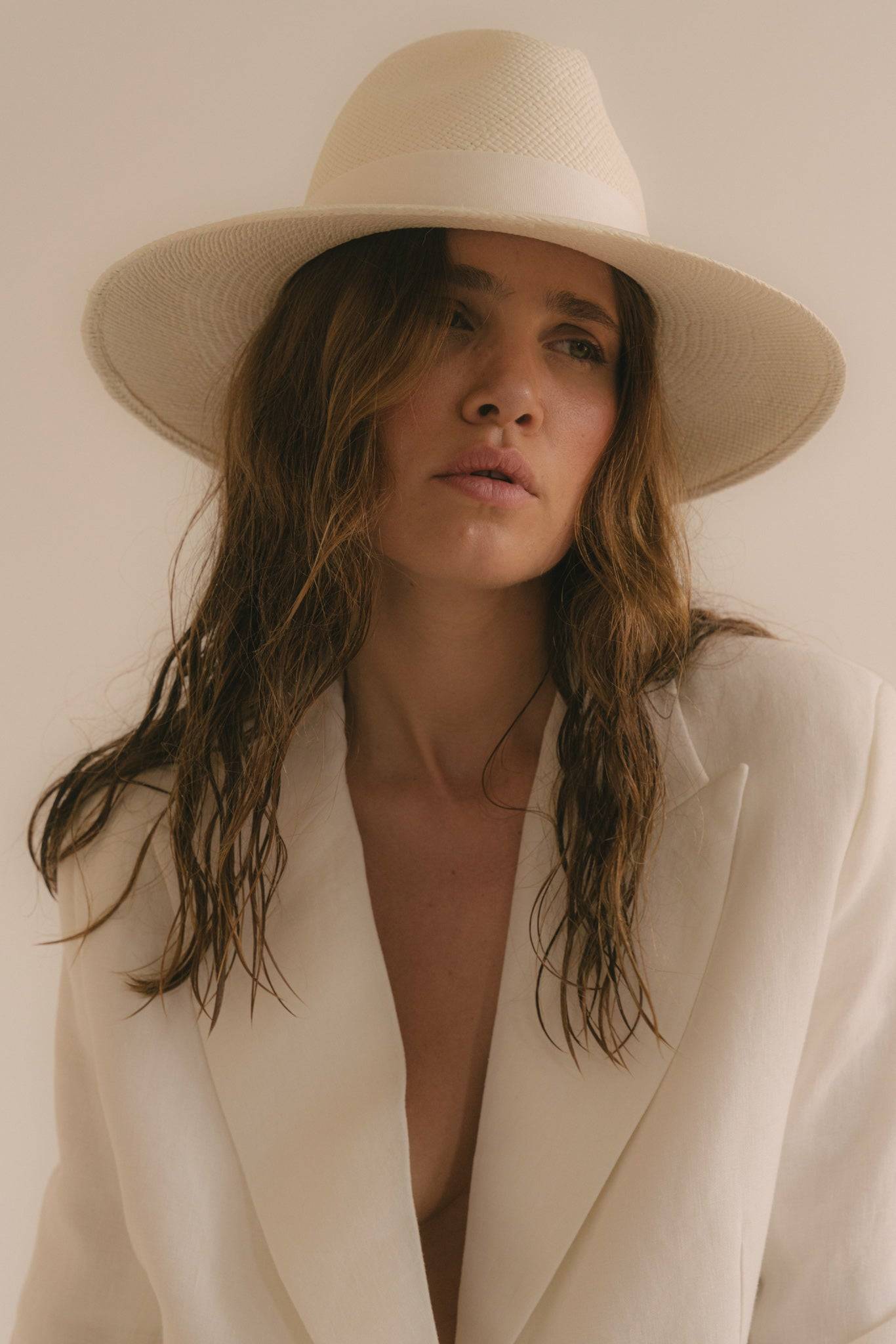 Close-up of a white wide-brimmed fedora hat, showcasing its fine craftsmanship. A perfect handcrafted summer hat for a refined and modern style.