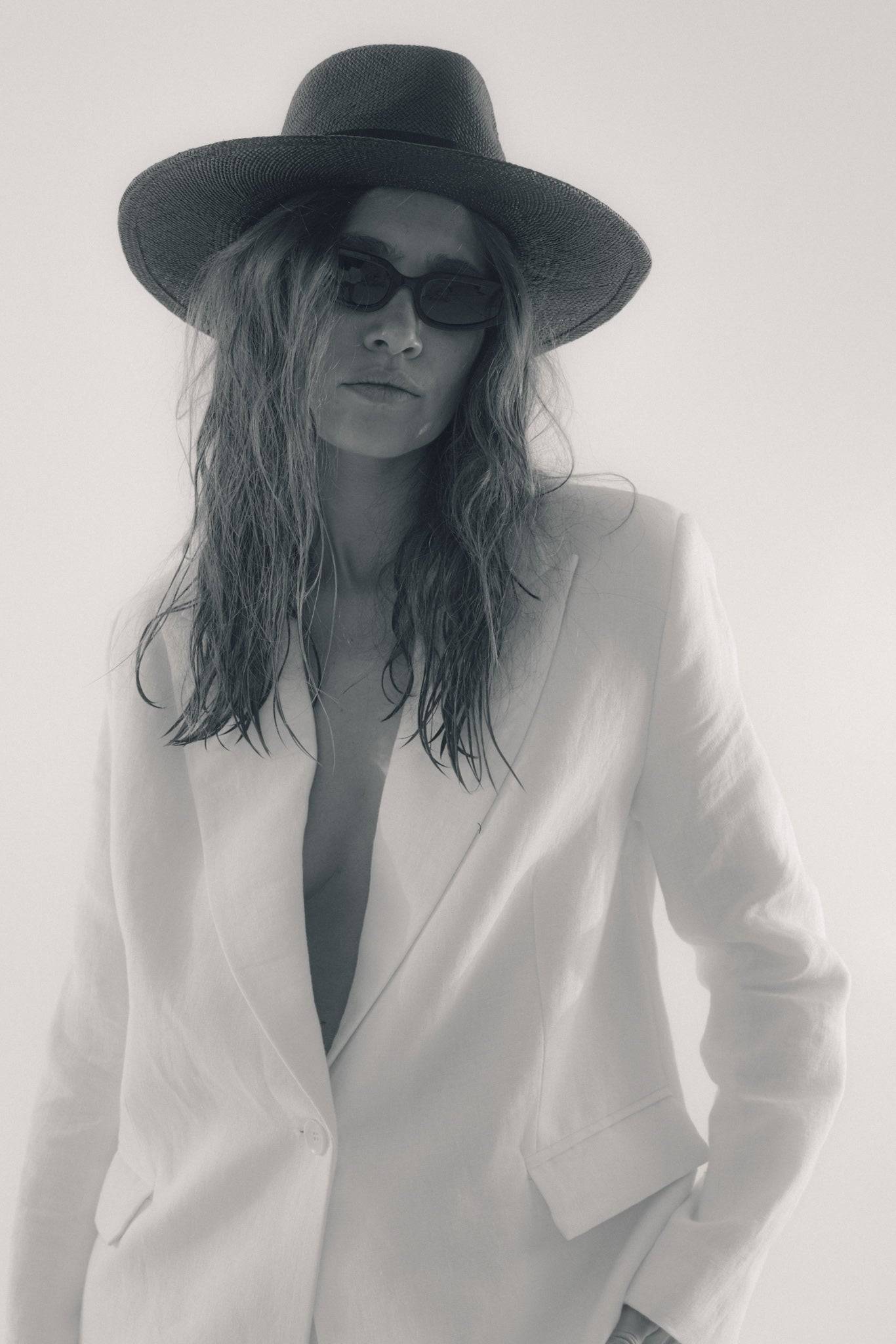 Black fedora straw hat styled with a white blazer, creating a chic monochrome look. Perfect for summer fashion and sun protection.