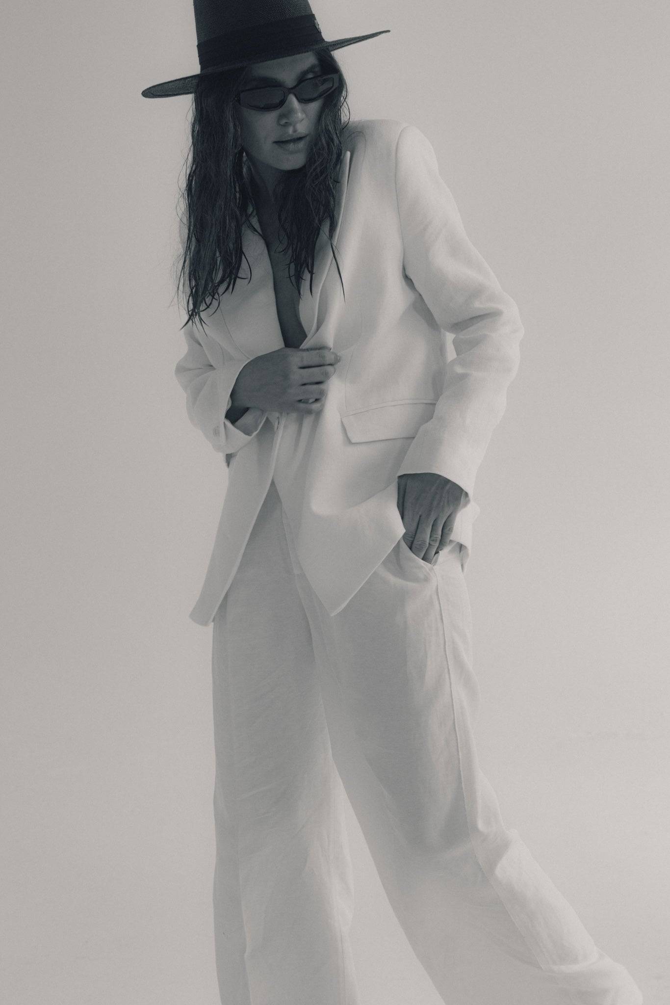 Black fedora straw hat paired with a white blazer and trousers, offering a bold and stylish contrast for a modern summer look.