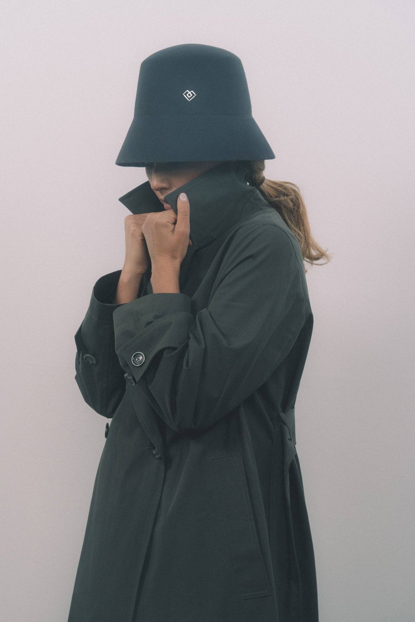 Elegant dark grey bucket hat made from fur felt, featuring a heart monogram. Styled with a trench coat for a refined fall and winter look.