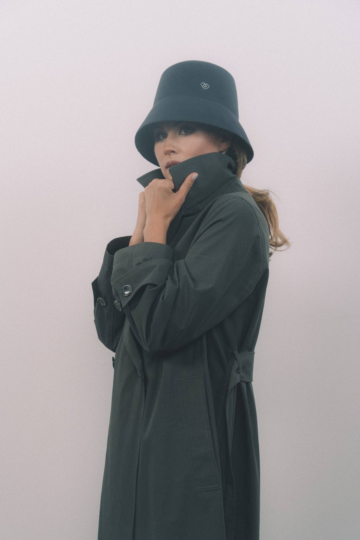 Luxury handcrafted dark grey bucket hat with a heart monogram, worn with a trench coat. A stylish and versatile accessory for any wardrobe.