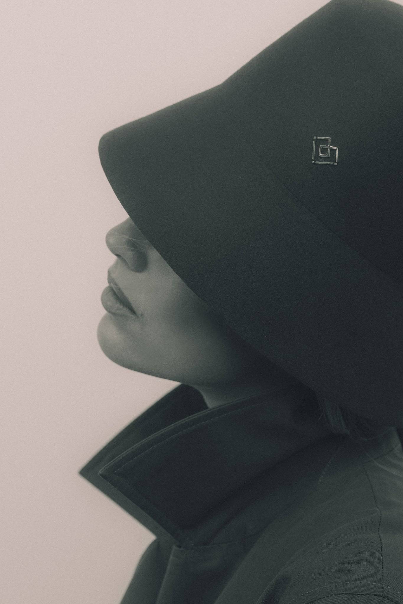 Close-up of a dark grey fur felt bucket hat with a heart monogram. A timeless and sophisticated fashion piece for modern elegance.
