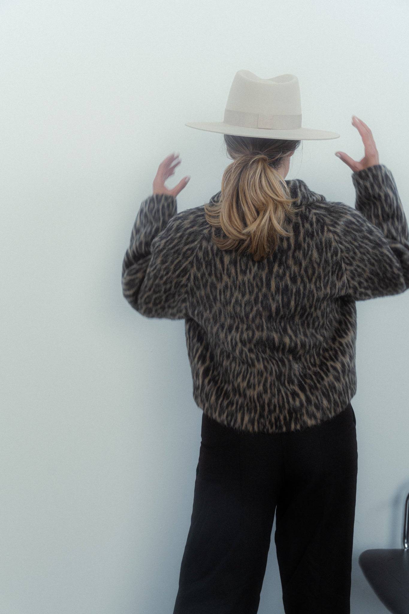 Back view of a cream fedora hat with a wide brim, styled with a leopard-print coat. A custom-made luxury millinery fedora for a bold fashion statement.