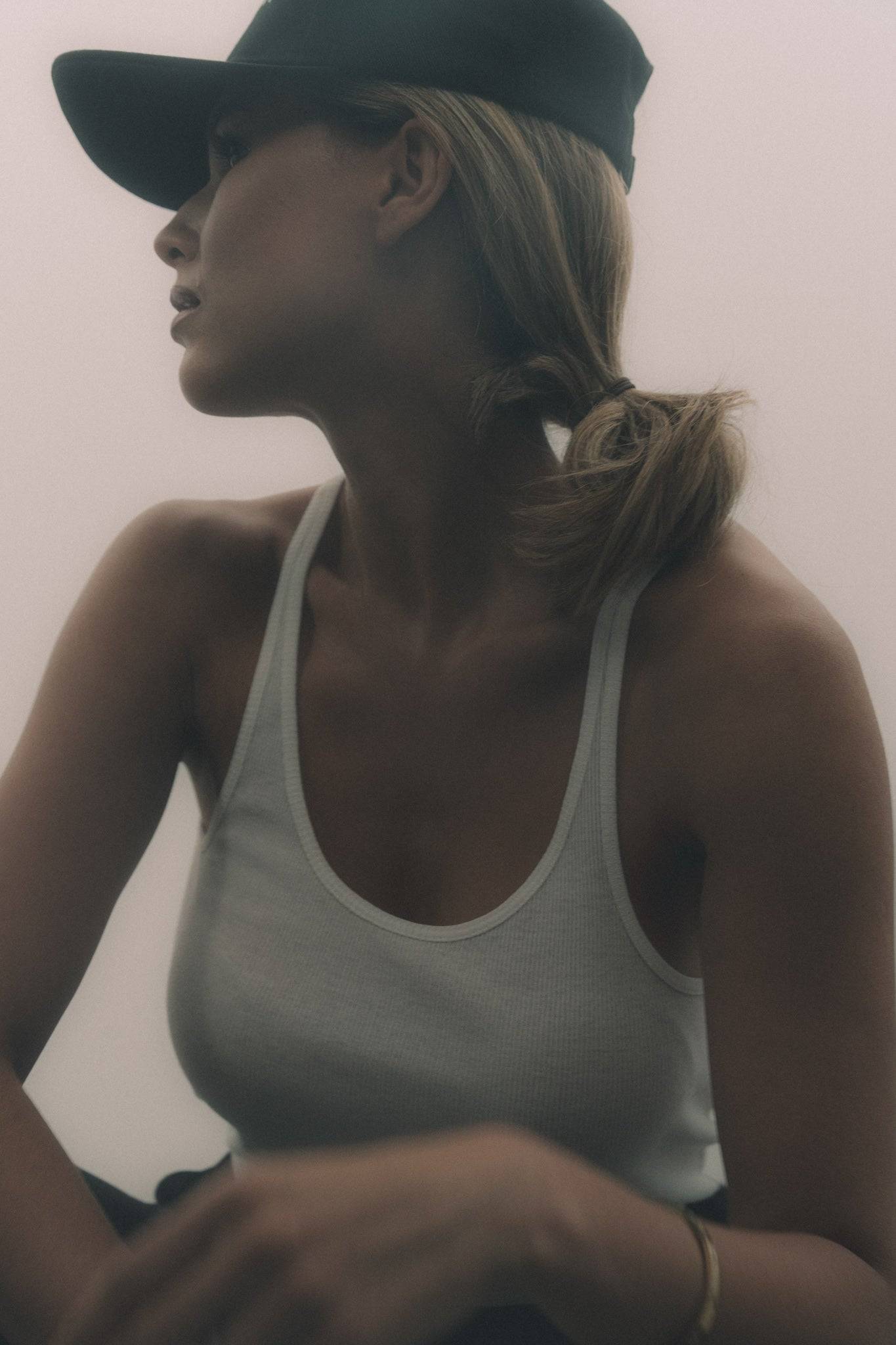 Minimalist black denim baseball cap paired with a white ribbed tank top, offering a sleek and modern casual look. A versatile cap for travel and street style.