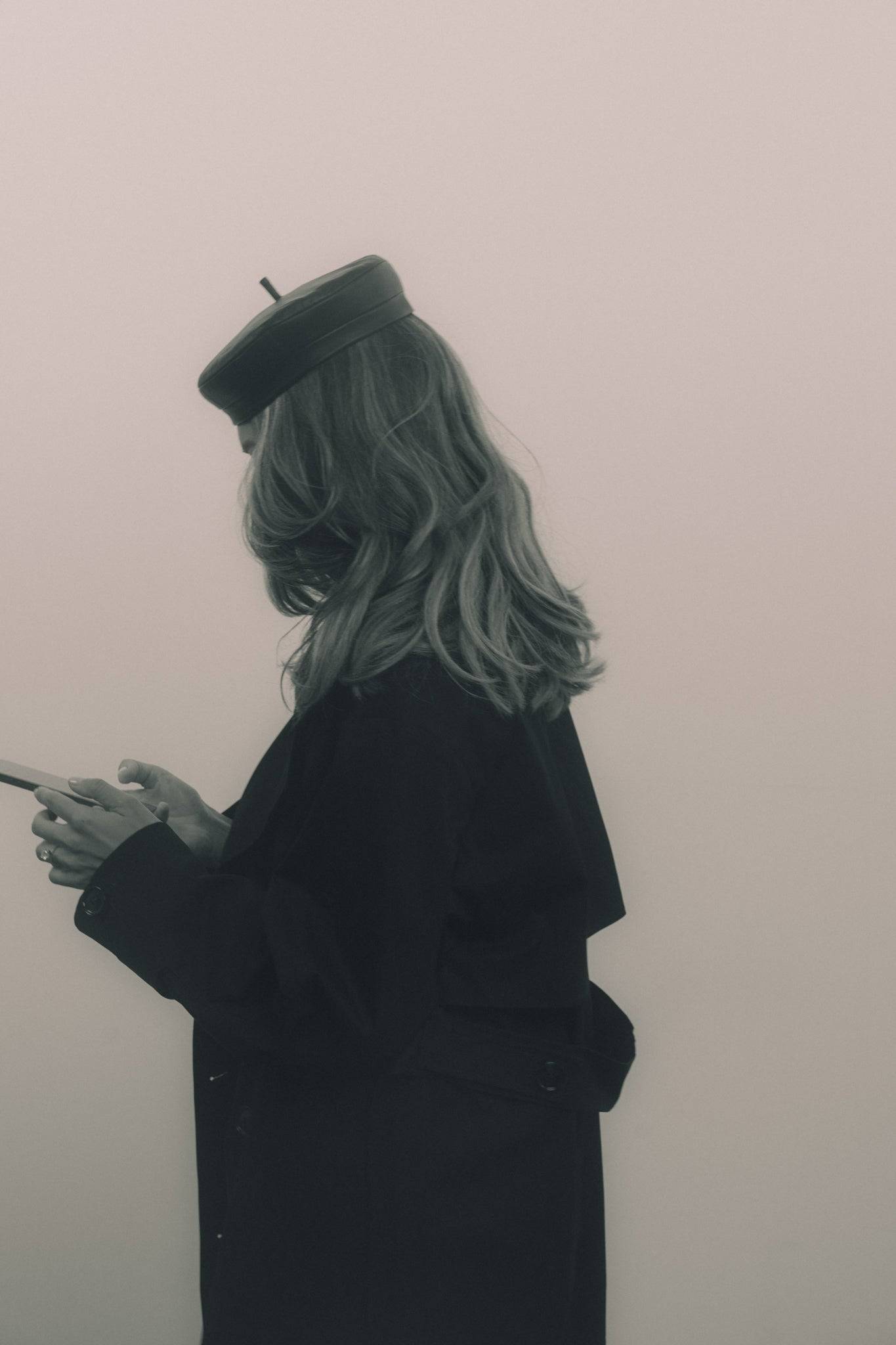 Minimalist black and white shot of a woman in a black leather beret, emphasizing its timeless elegance. A statement accessory for any wardrobe.