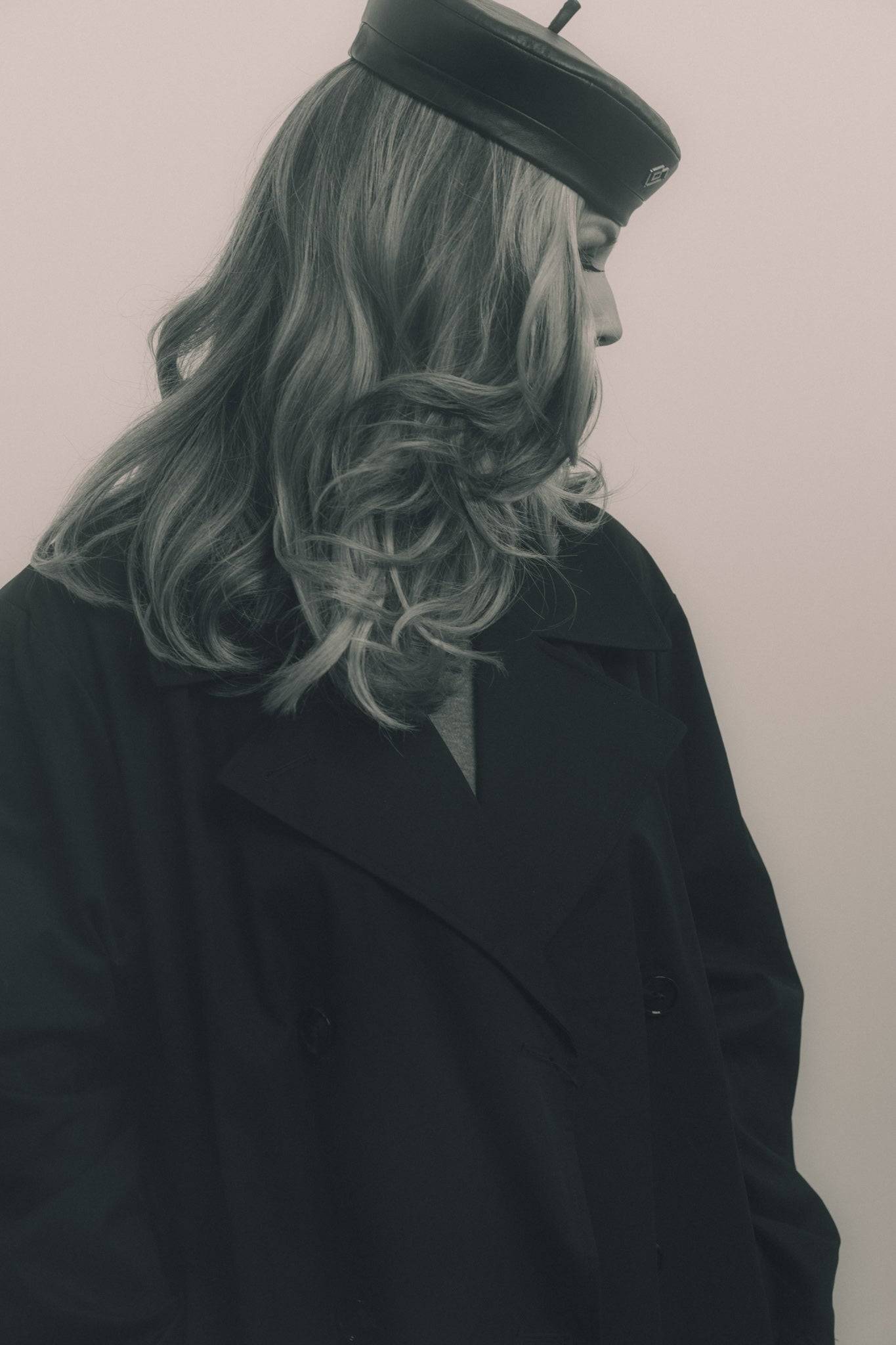 Artistic monochrome image of a woman in a black leather beret, styled with a dark coat. A bold and trendy leather accessory.