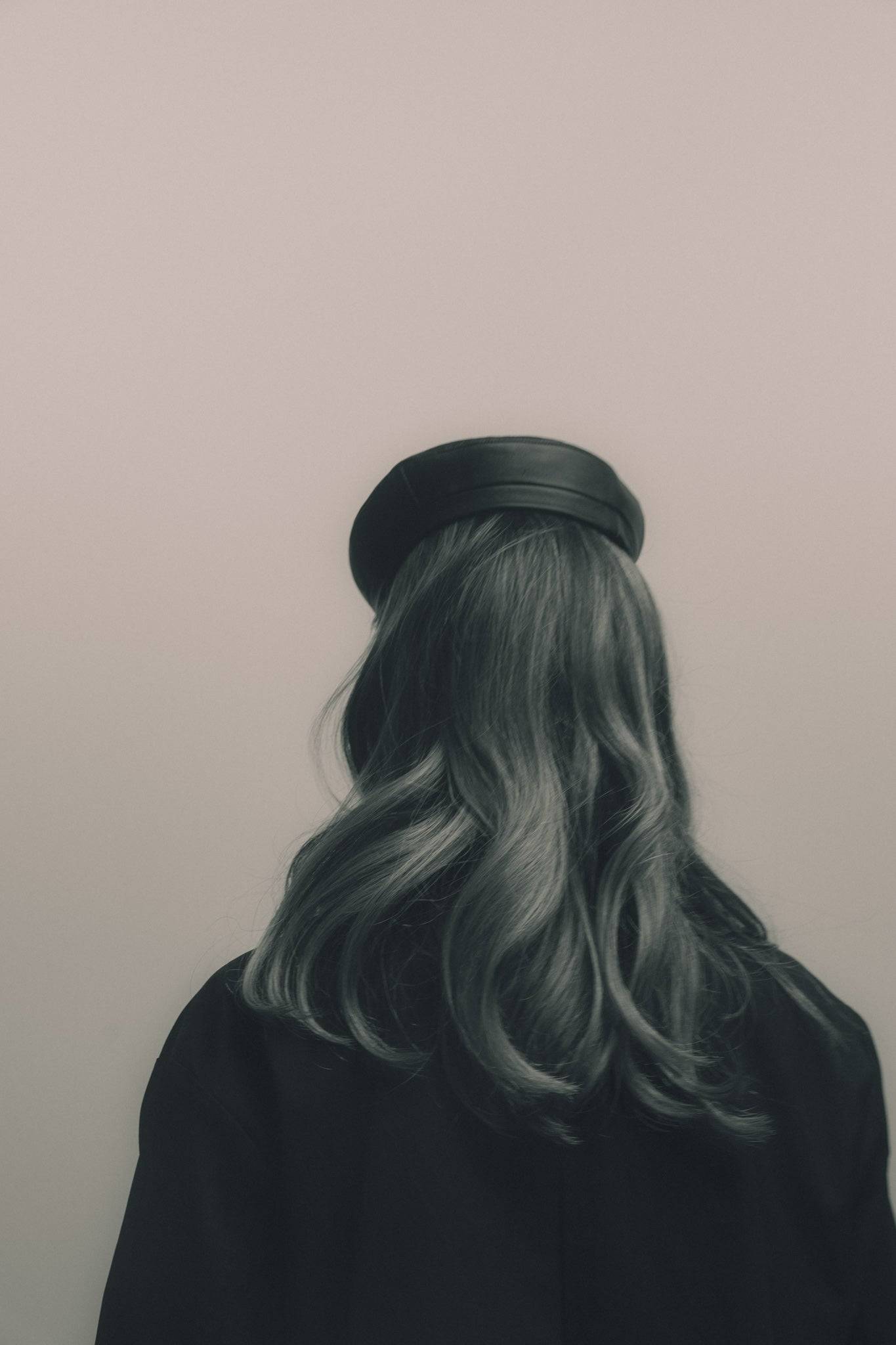 Back view of a black leather beret, showcasing its smooth texture and structured fit. A luxury fashion piece for a refined look.