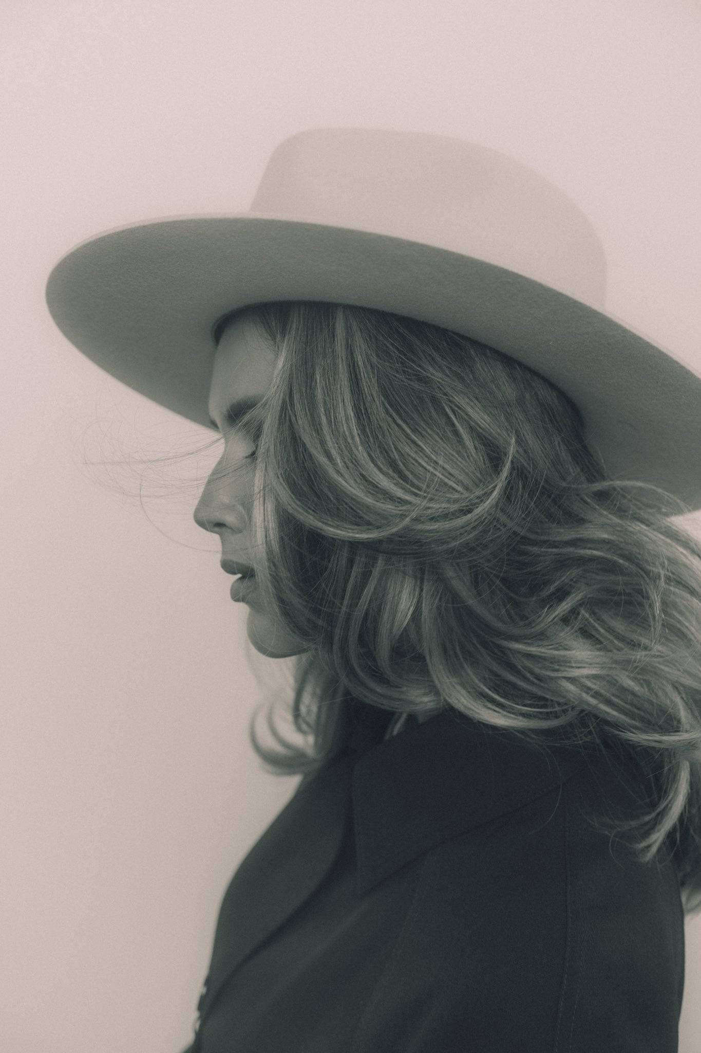Artisan ivory fedora hat with a structured brim, worn by a woman with flowing hair for a timeless and elegant aesthetic.