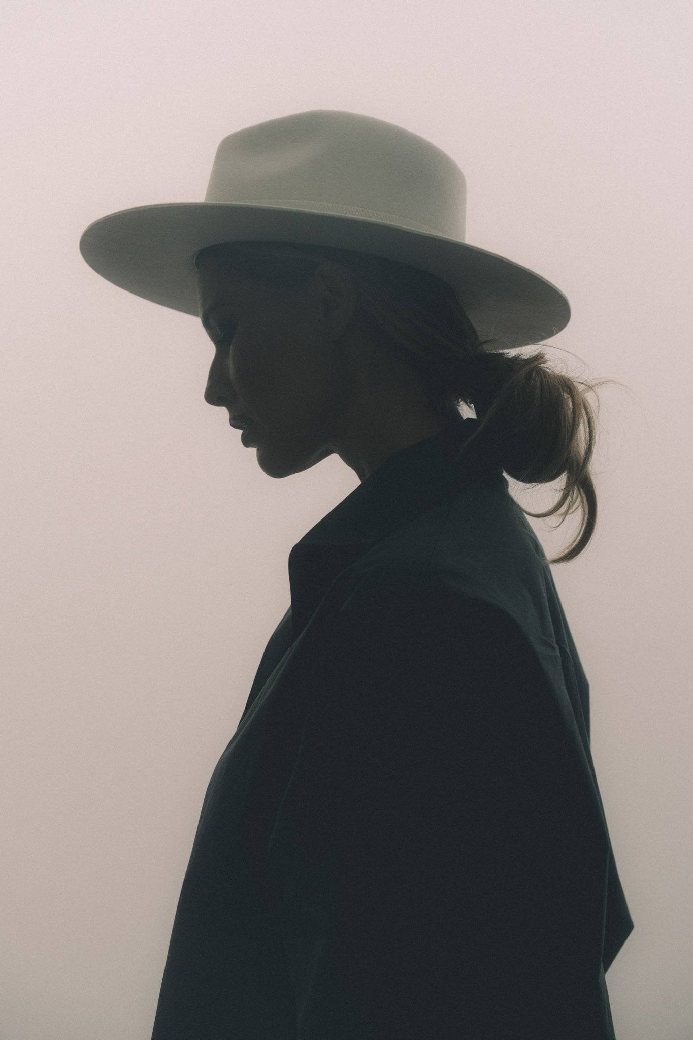 Silhouette of a woman wearing a luxury ivory fedora hat, highlighting its structured design and timeless elegance.