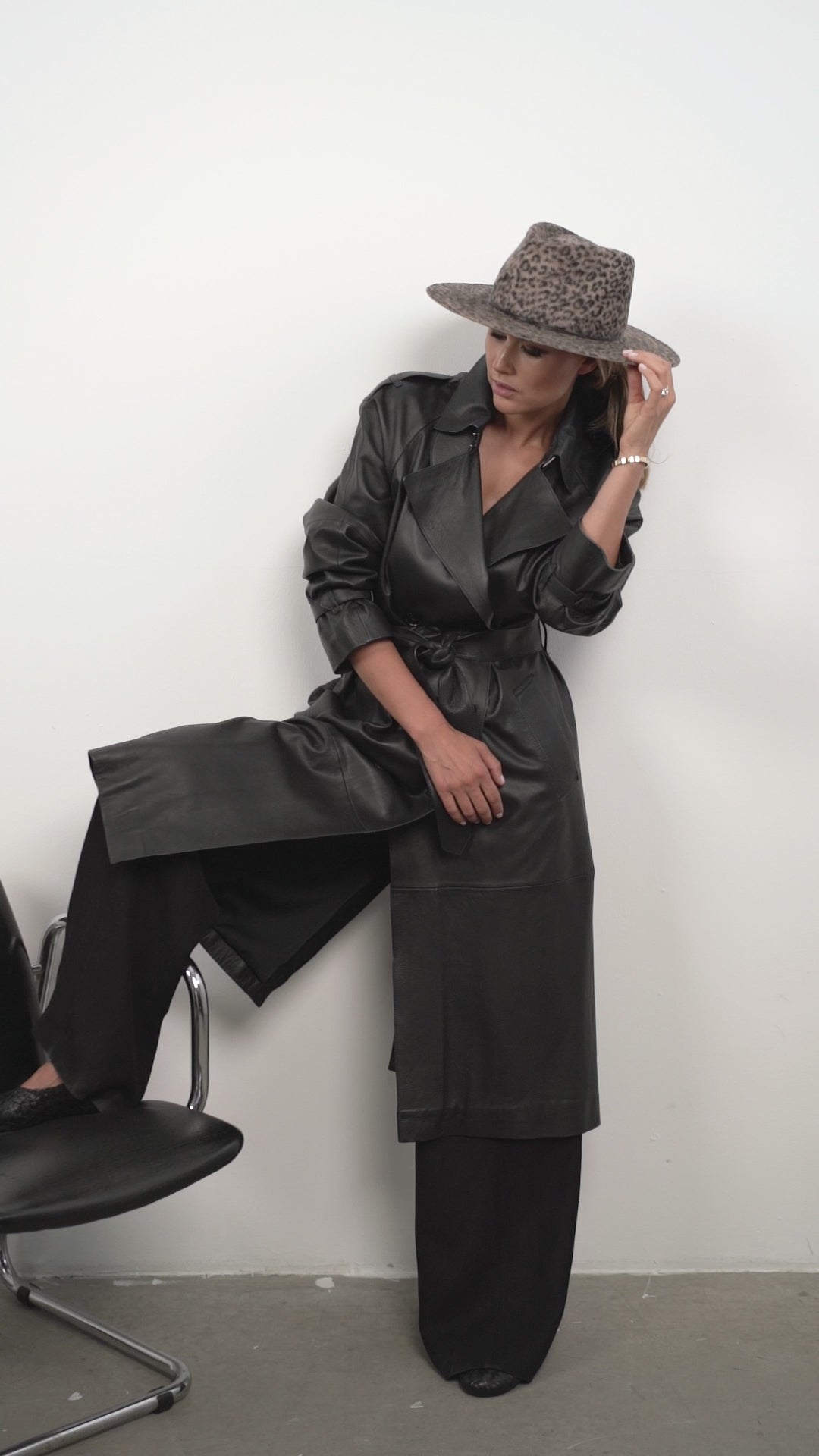 Leopard print fedora hat styled with a black leather coat and wide-leg pants. A modern and elegant fashion piece for any occasion.