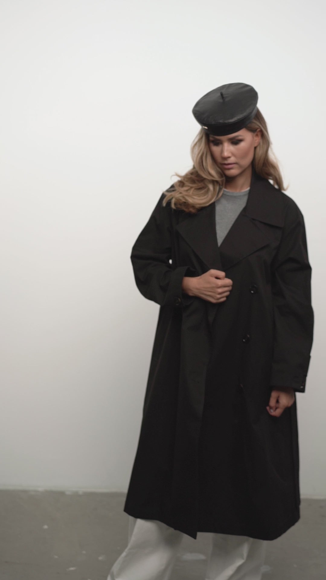 Elegant black leather beret paired with a long black coat for a sophisticated street-style outfit. Premium handcrafted leather accessory.